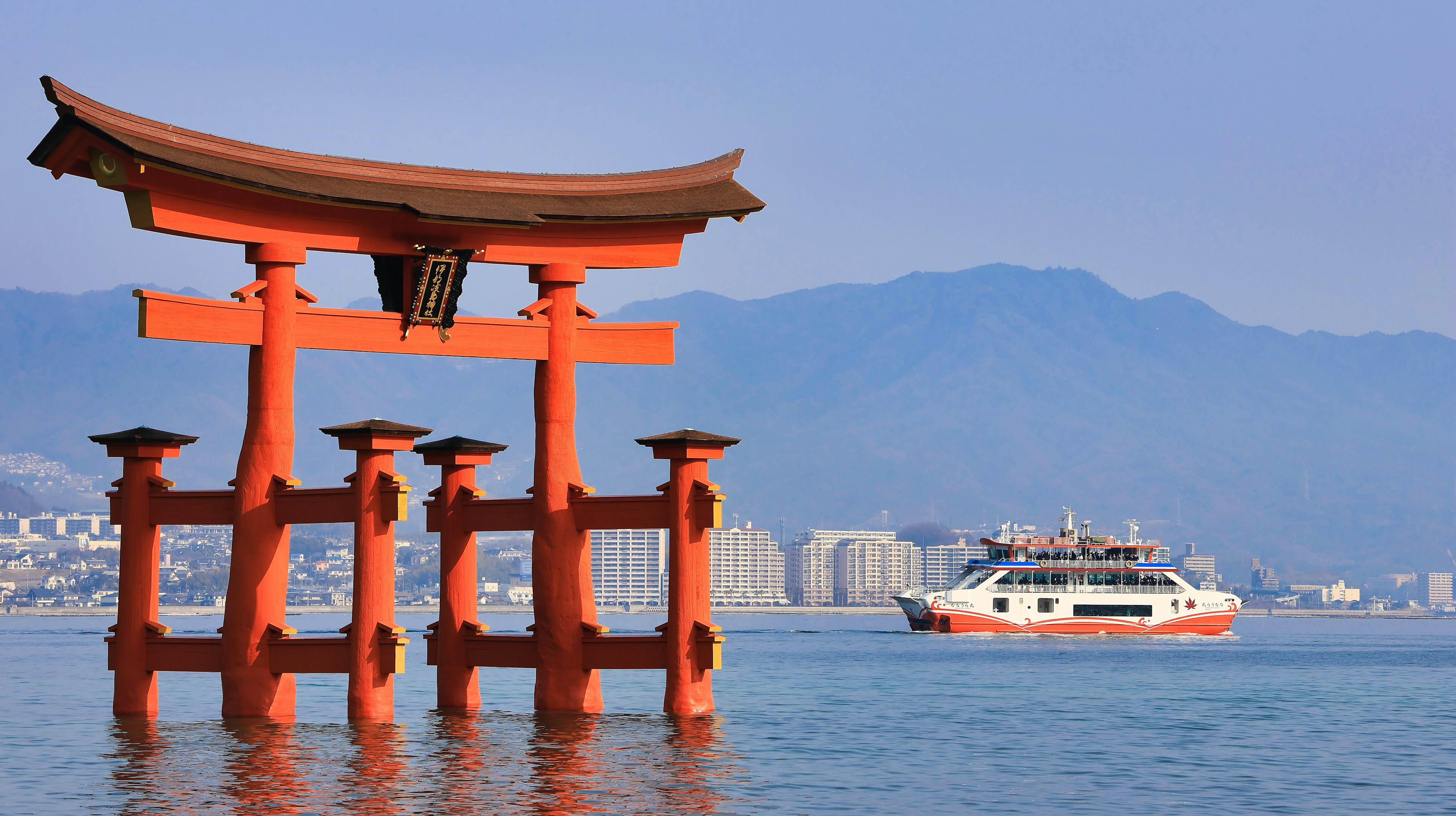 Gerbang torii merah di laut dengan kapal di dekatnya