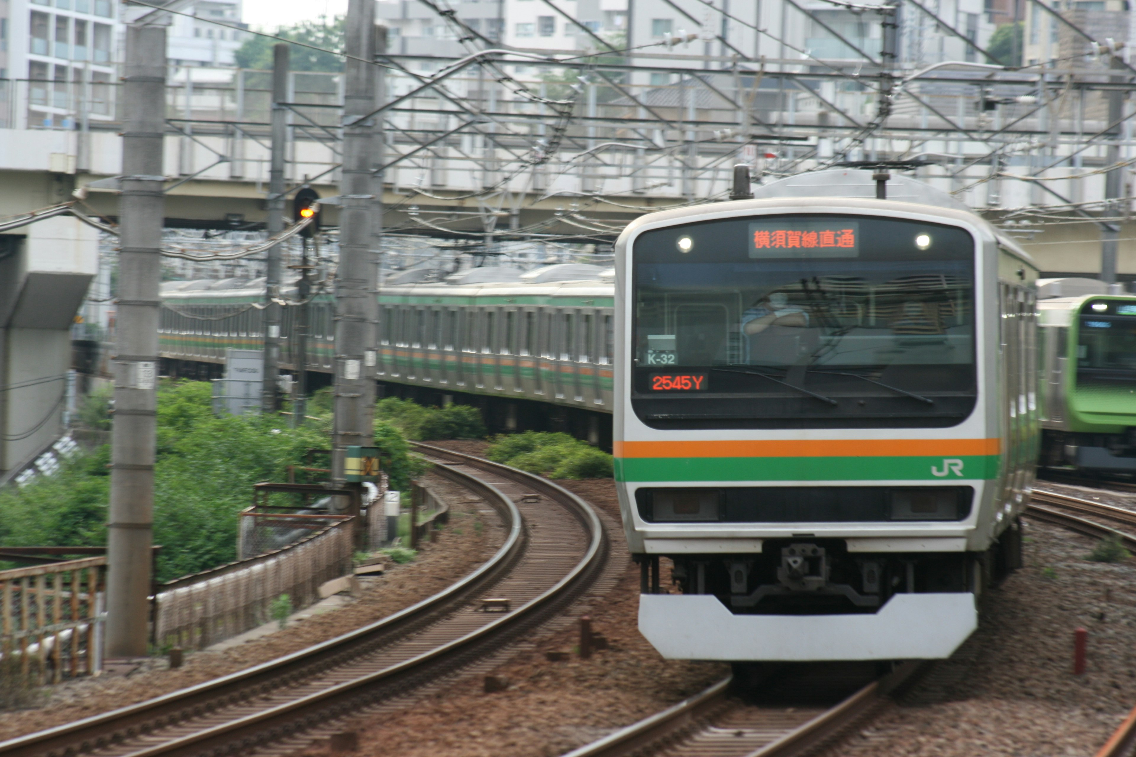 緑とオレンジのストライプが特徴的な電車が曲がりくねった線路を走る