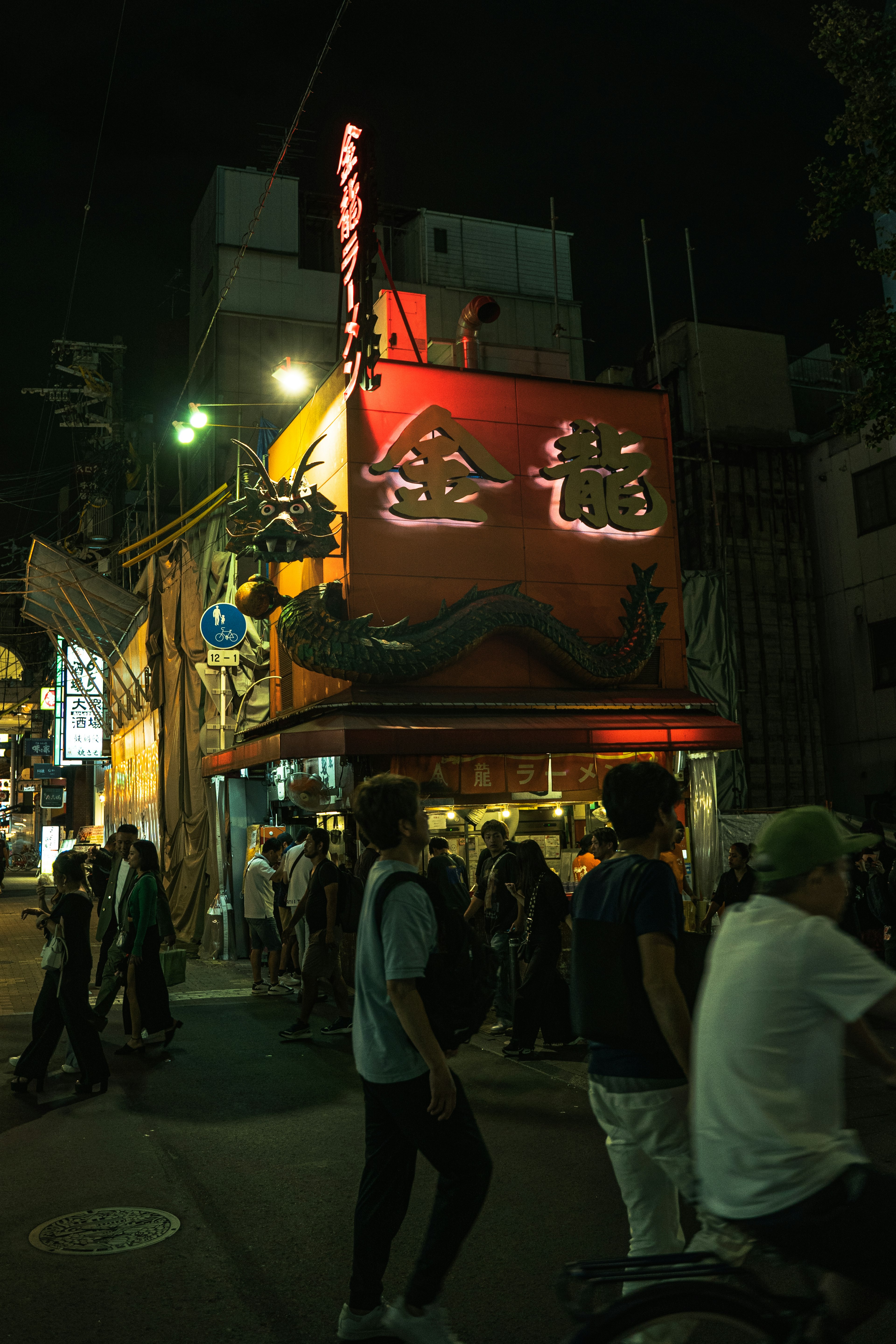 ฝูงชนหลากหลายคนที่รวมตัวอยู่รอบร้านสีแดงสดในตอนกลางคืน