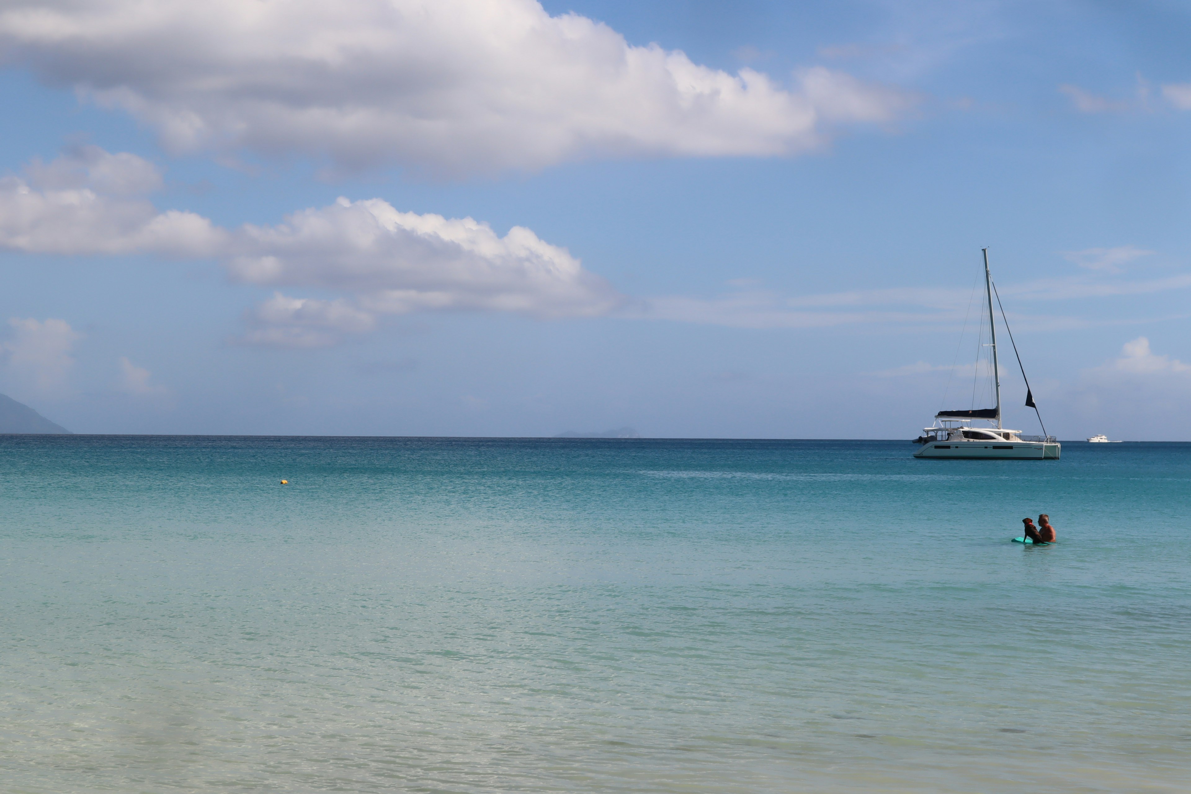 Vista panoramica di uno yacht su acque blu chiare con una spiaggia di sabbia