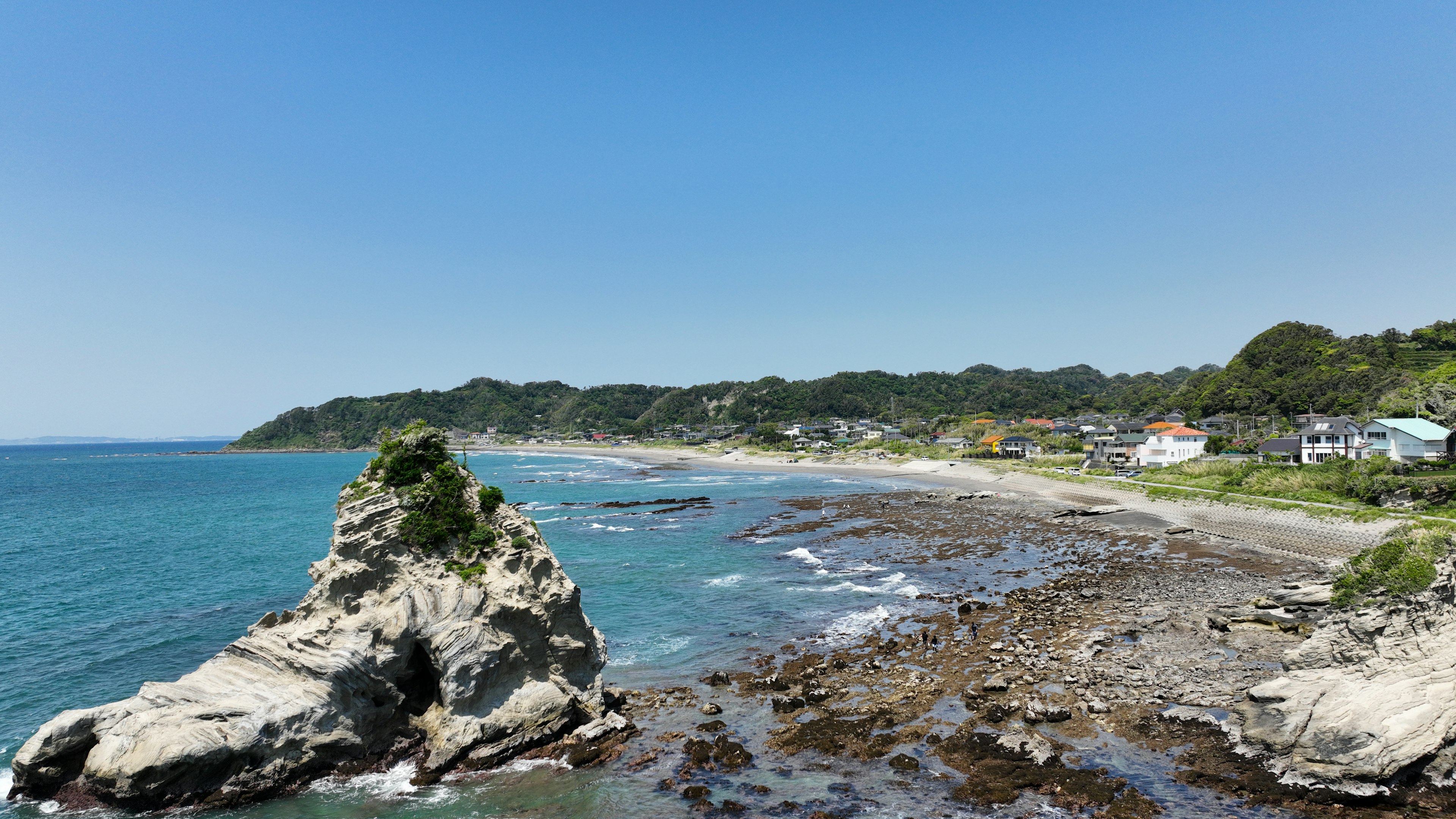 Pemandangan pantai dengan batu karang dan langit biru cerah