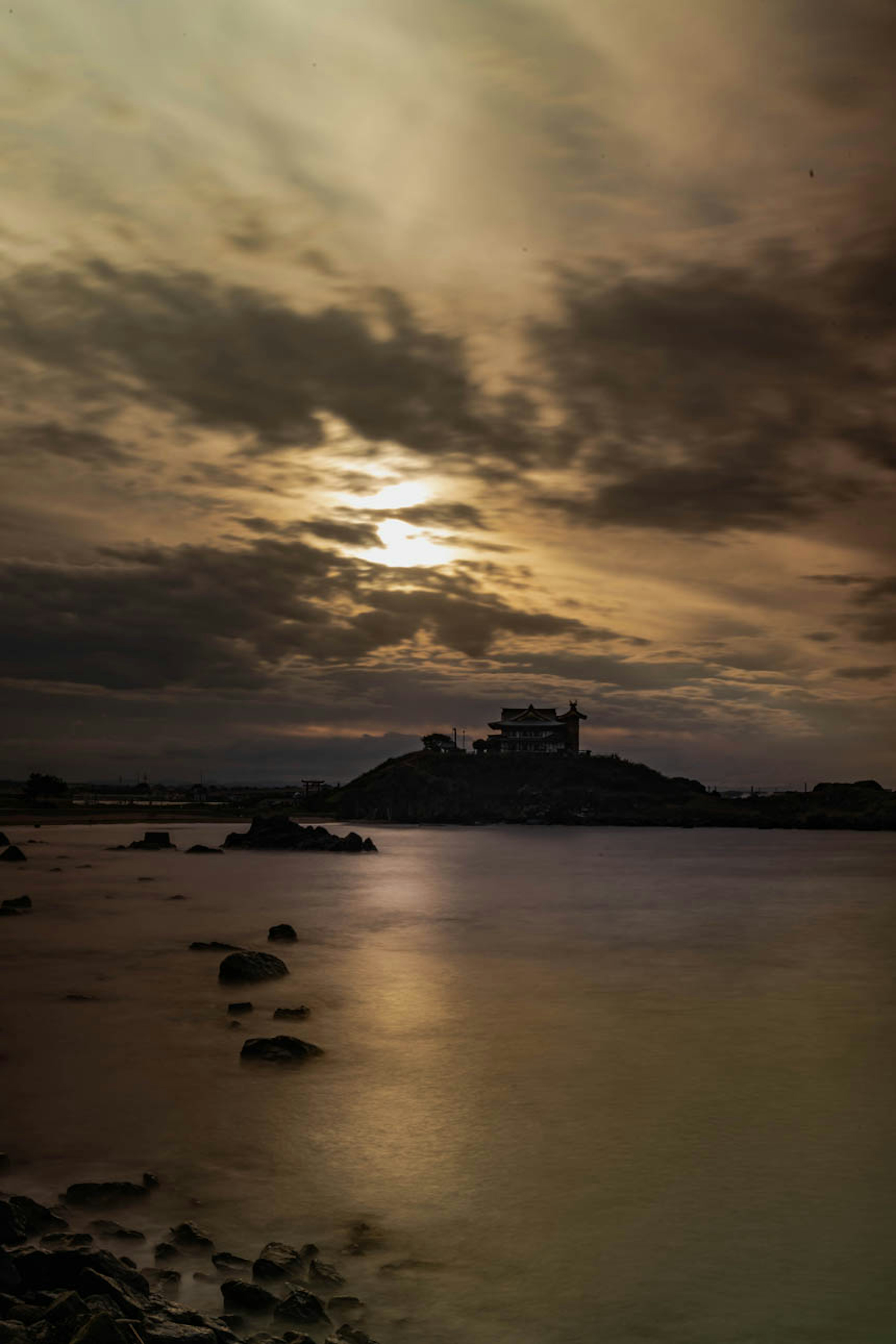 Coastal landscape with a small island under a cloudy sunset