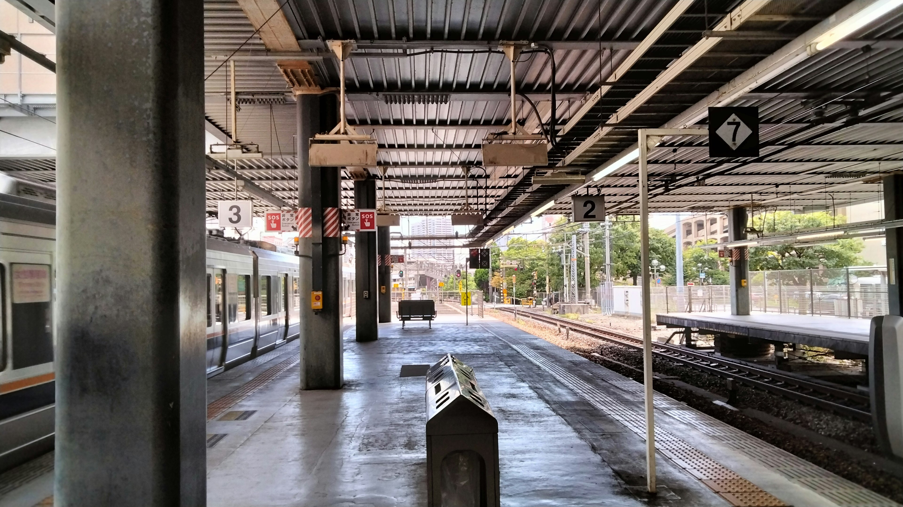 Plataforma de estación tranquila con pasajeros esperando y trenes estacionados