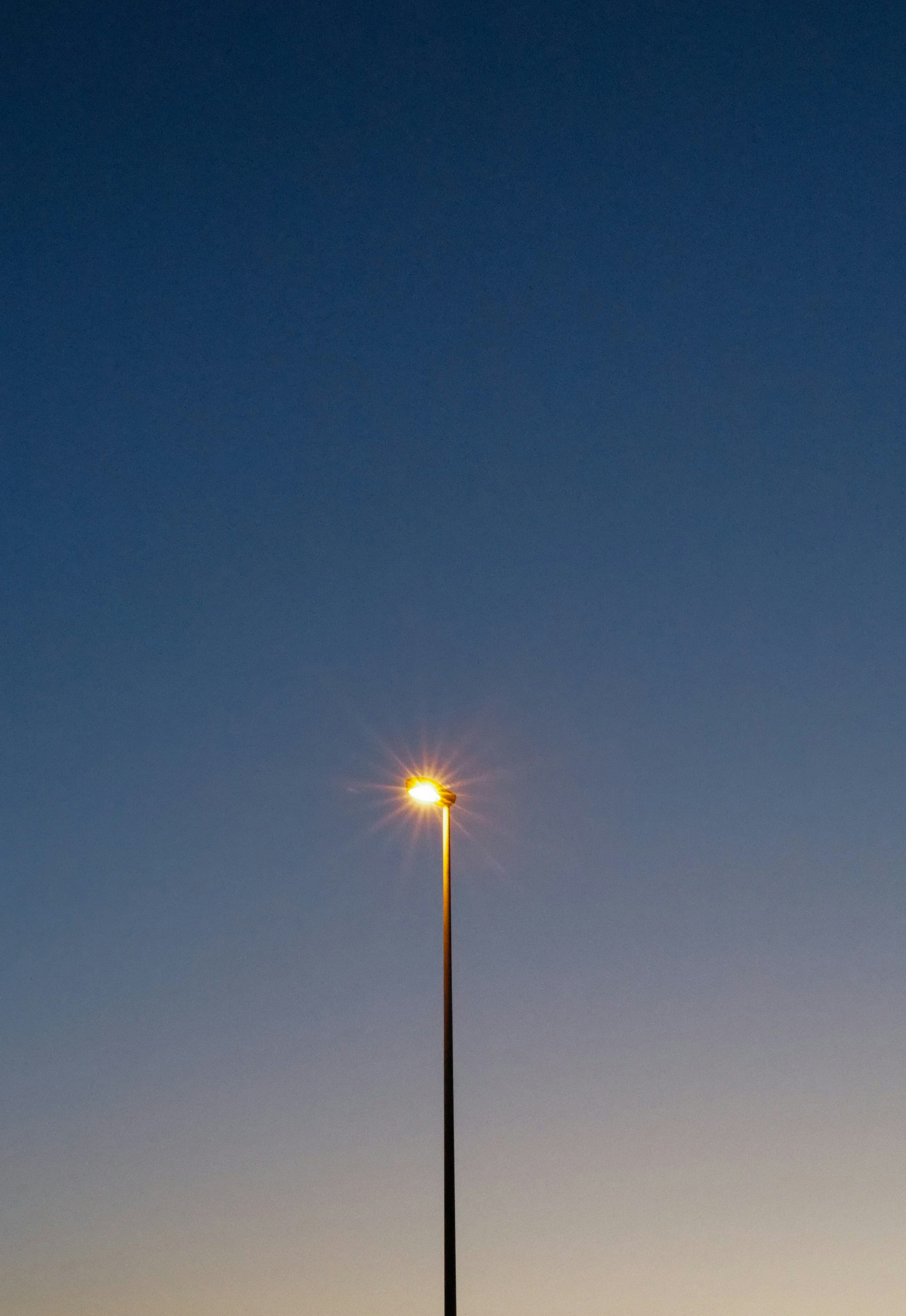 Eine Straßenlaterne leuchtet vor einem dunklen blauen Abendhimmel