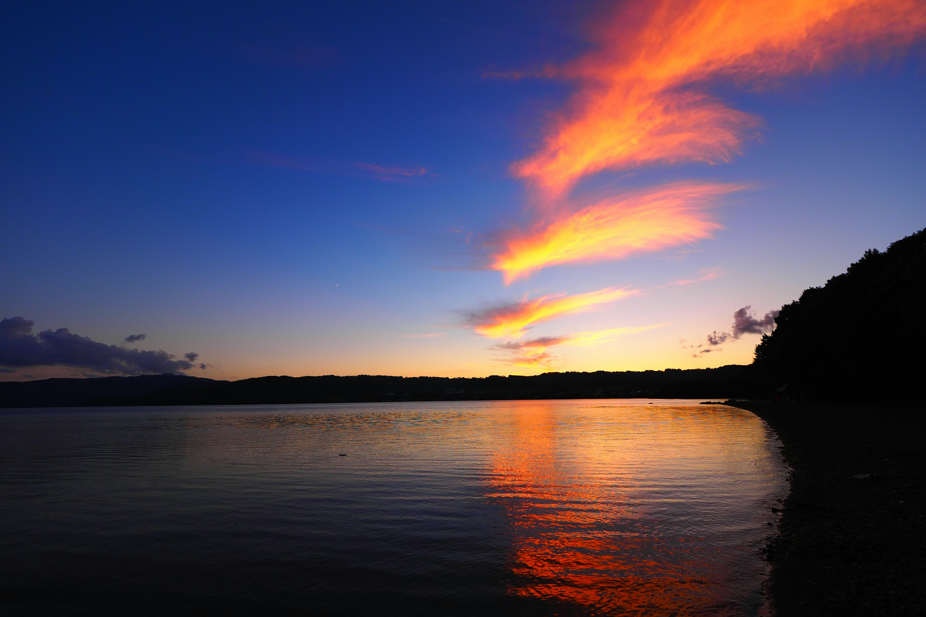 Wunderschöner Sonnenuntergangshimmel mit lebhaften Wolken über einem ruhigen See