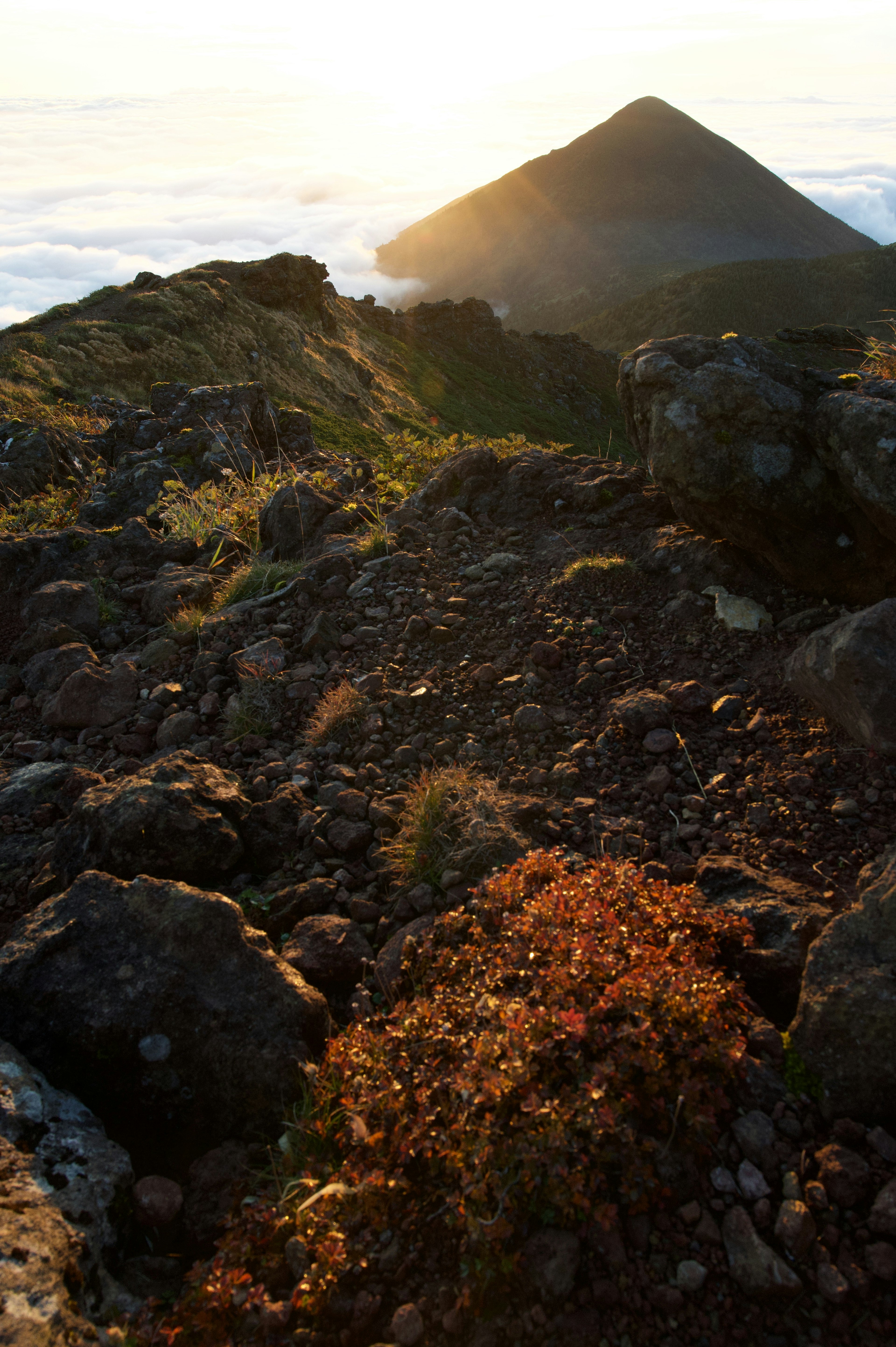 Atardecer iluminando un pico montañoso y un paisaje rocoso