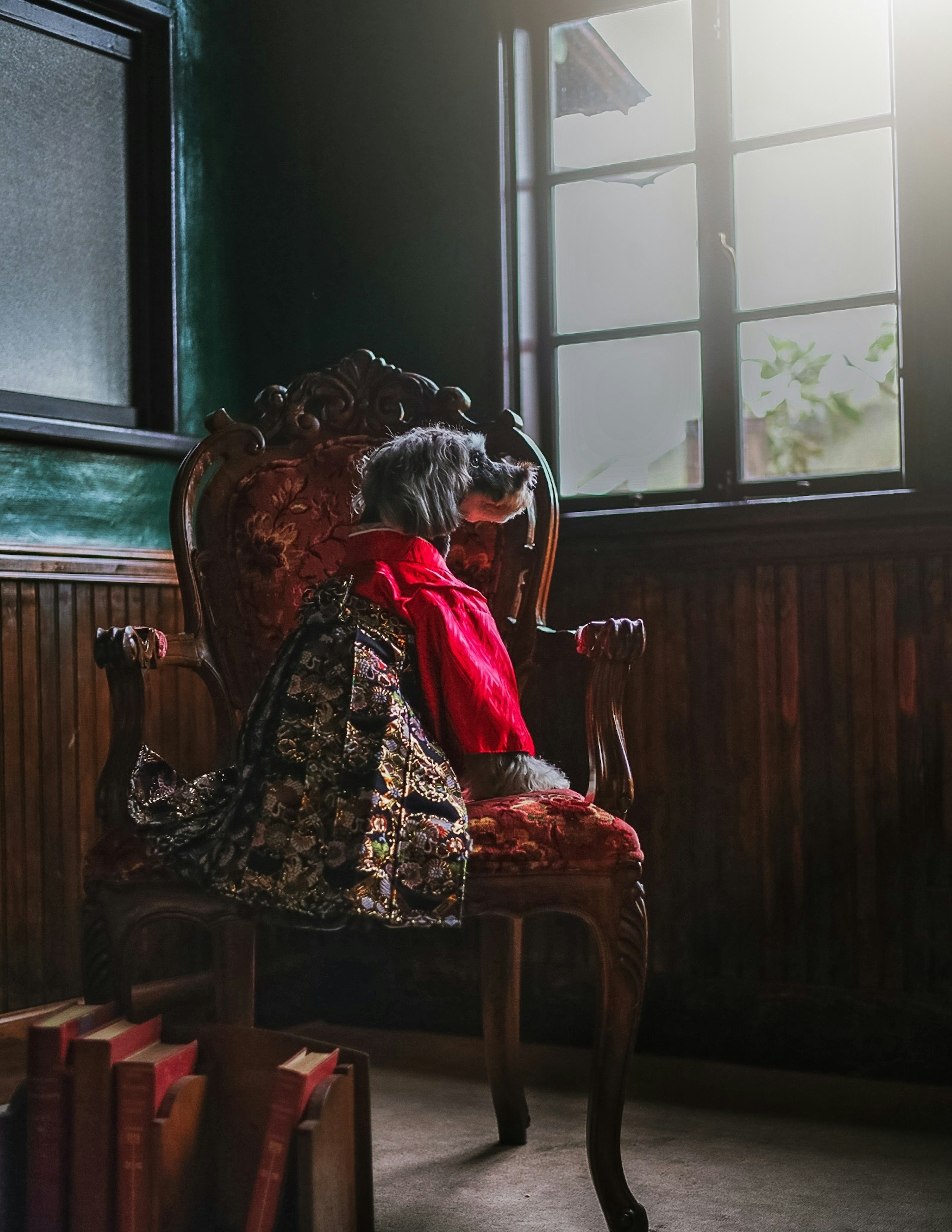 Une poupée en tenue rouge assise sur une chaise antique à l'intérieur