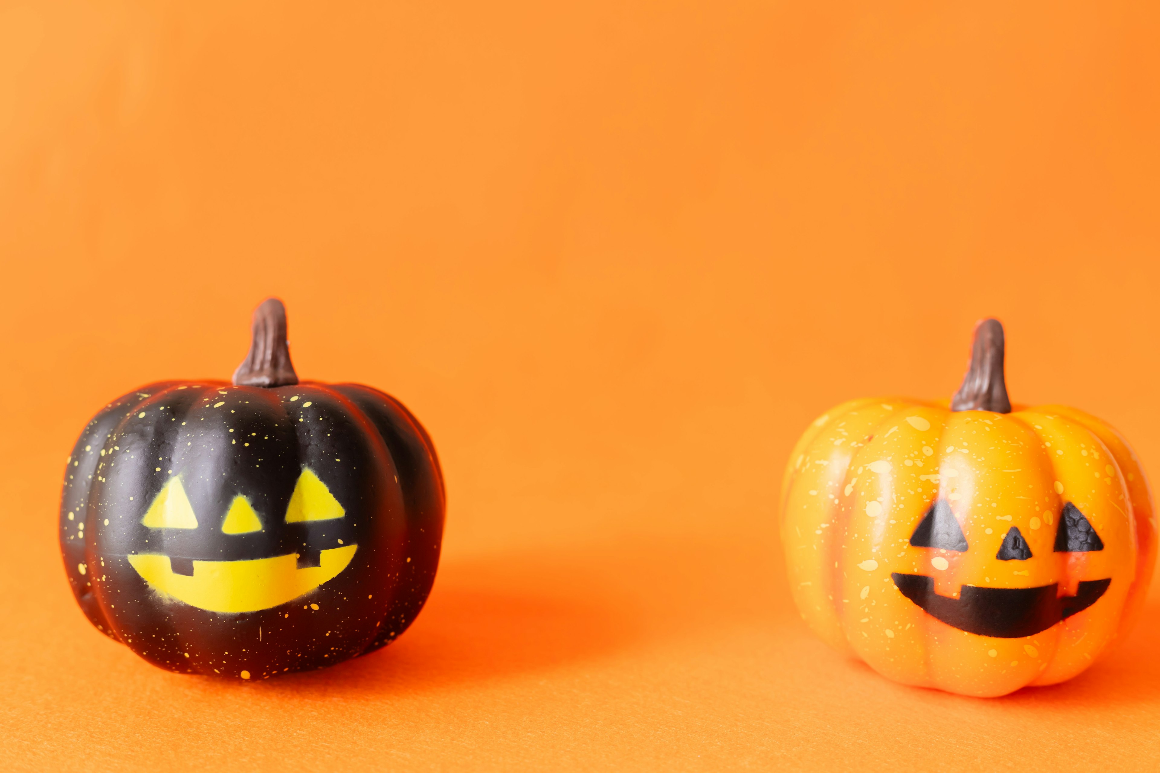 Calabazas de Halloween negras y naranjas sobre un fondo naranja