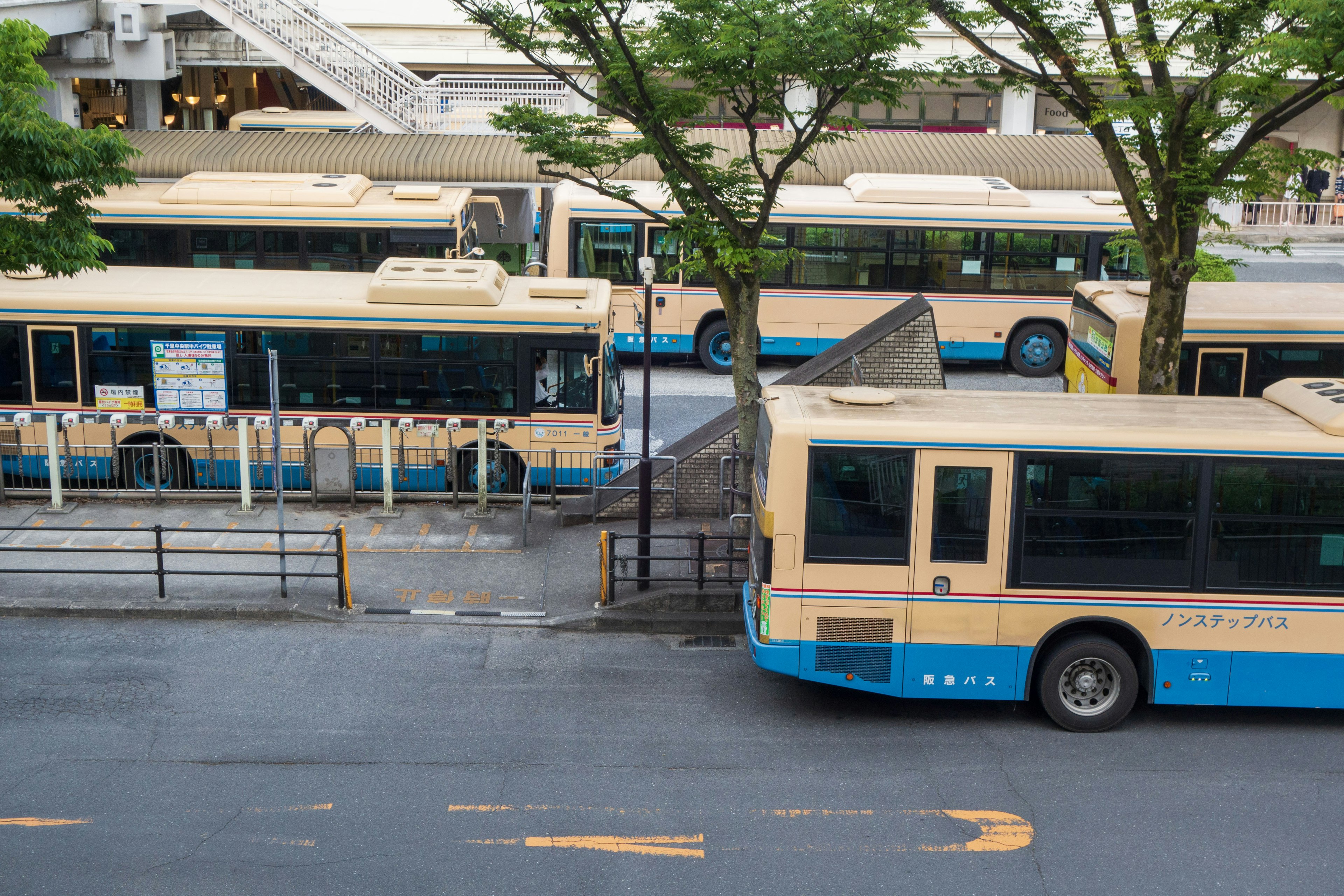 Image d'une station de bus avec plusieurs bus garés et des arbres à proximité