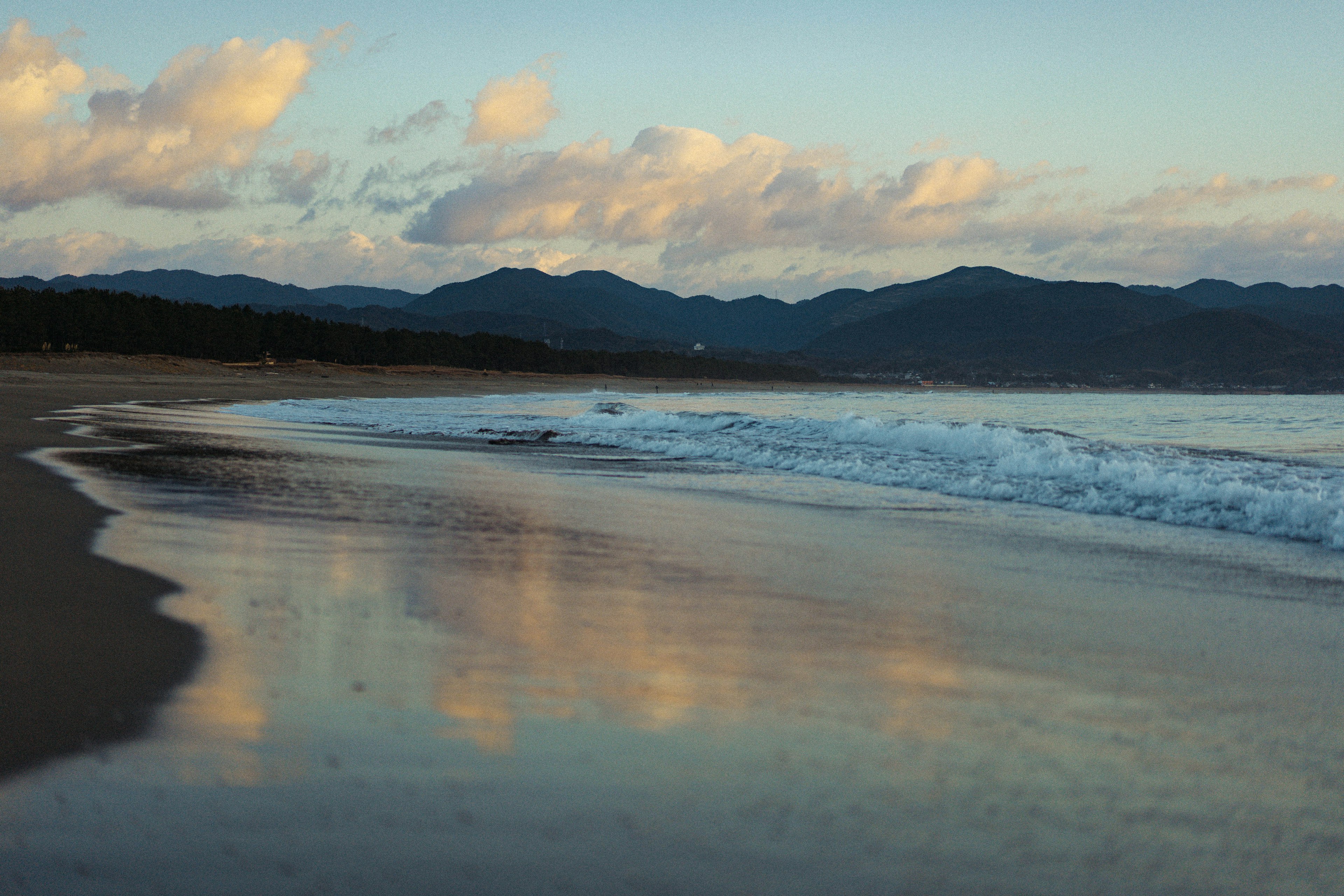 Scène côtière avec des vagues et des reflets de nuages et de montagnes