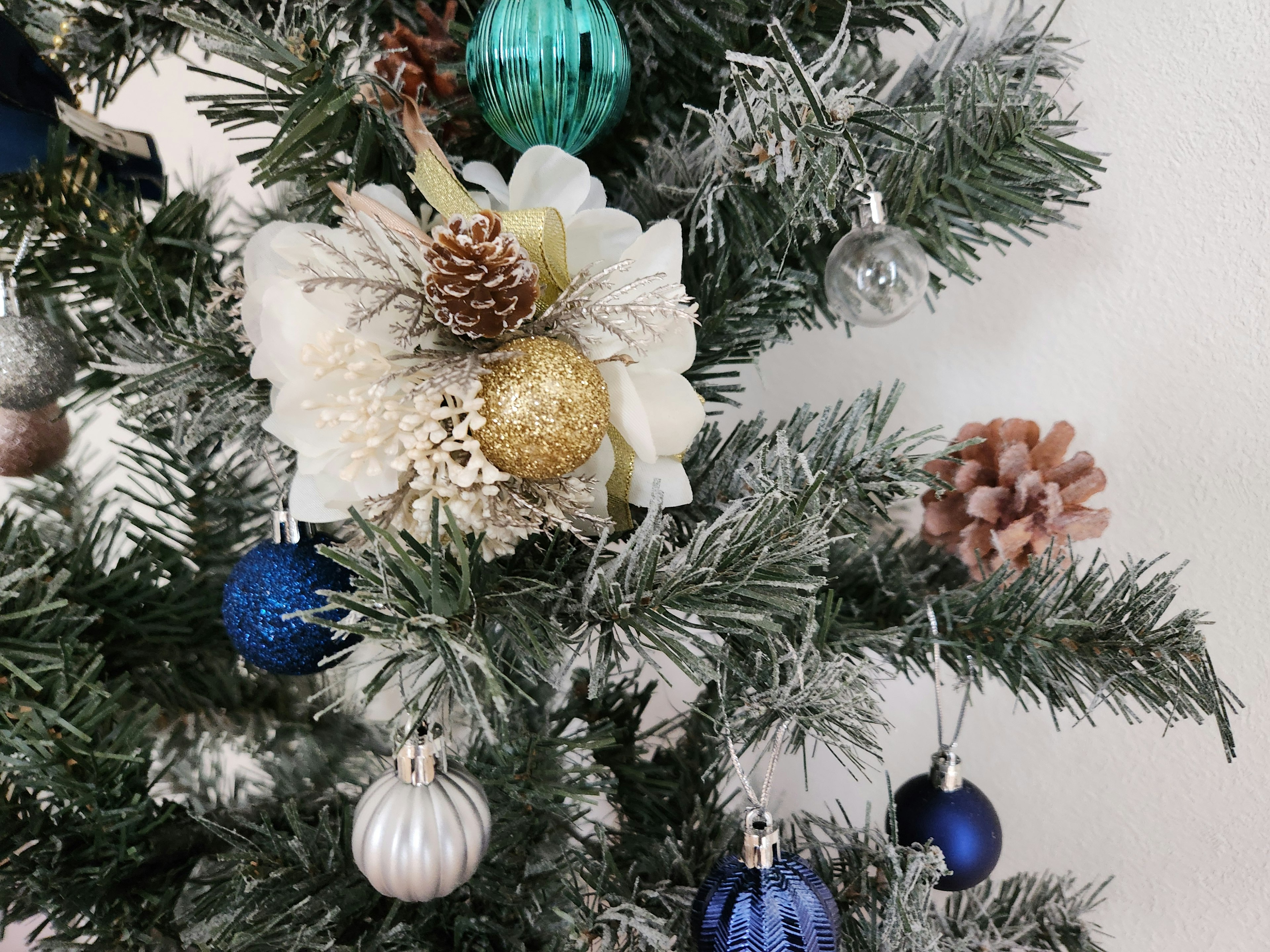 Weihnachtsbaum dekoriert mit weißen Blumen und bunten Ornamenten