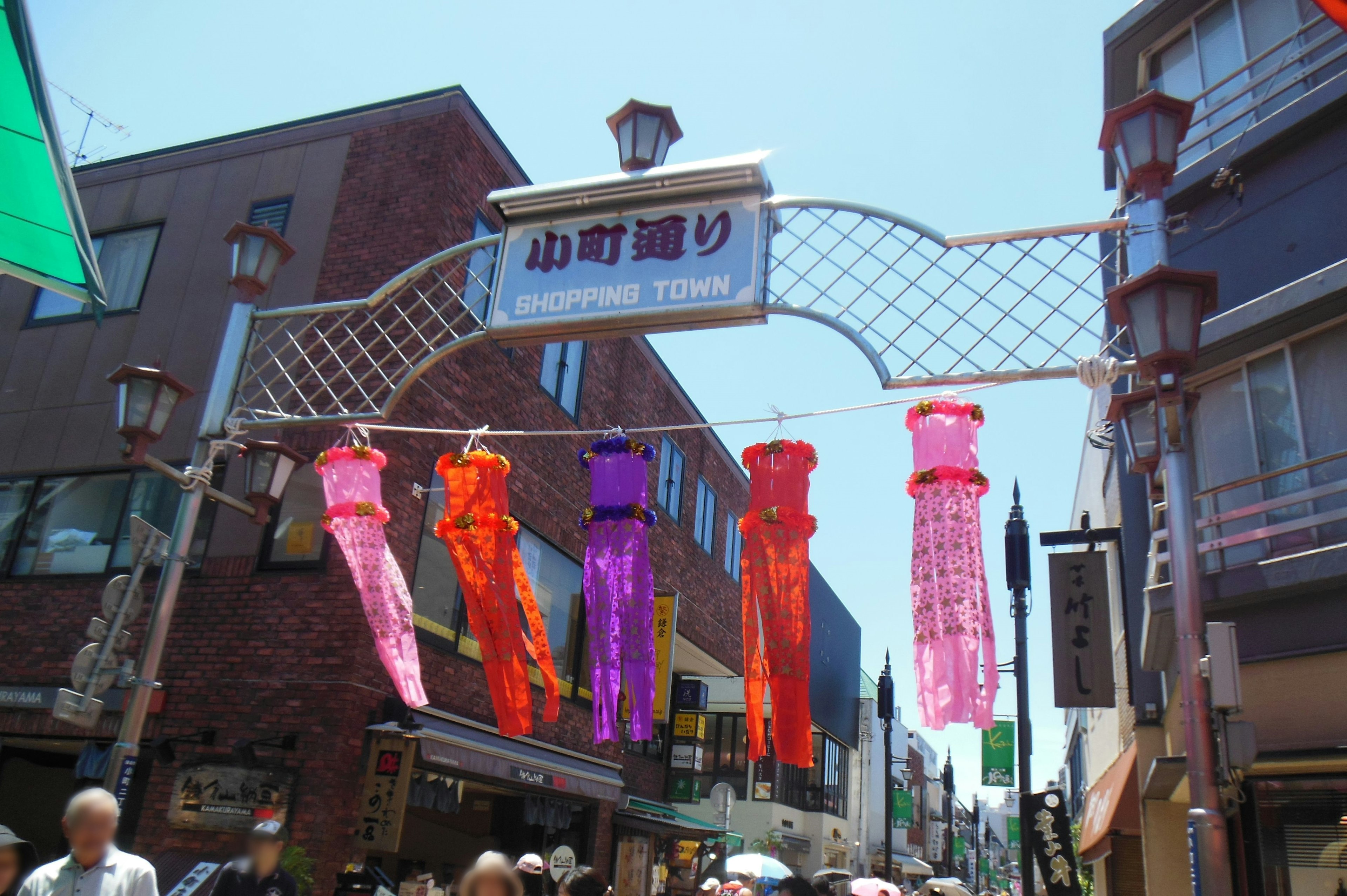 Colorful decorations hanging from an archway in a lively shopping street