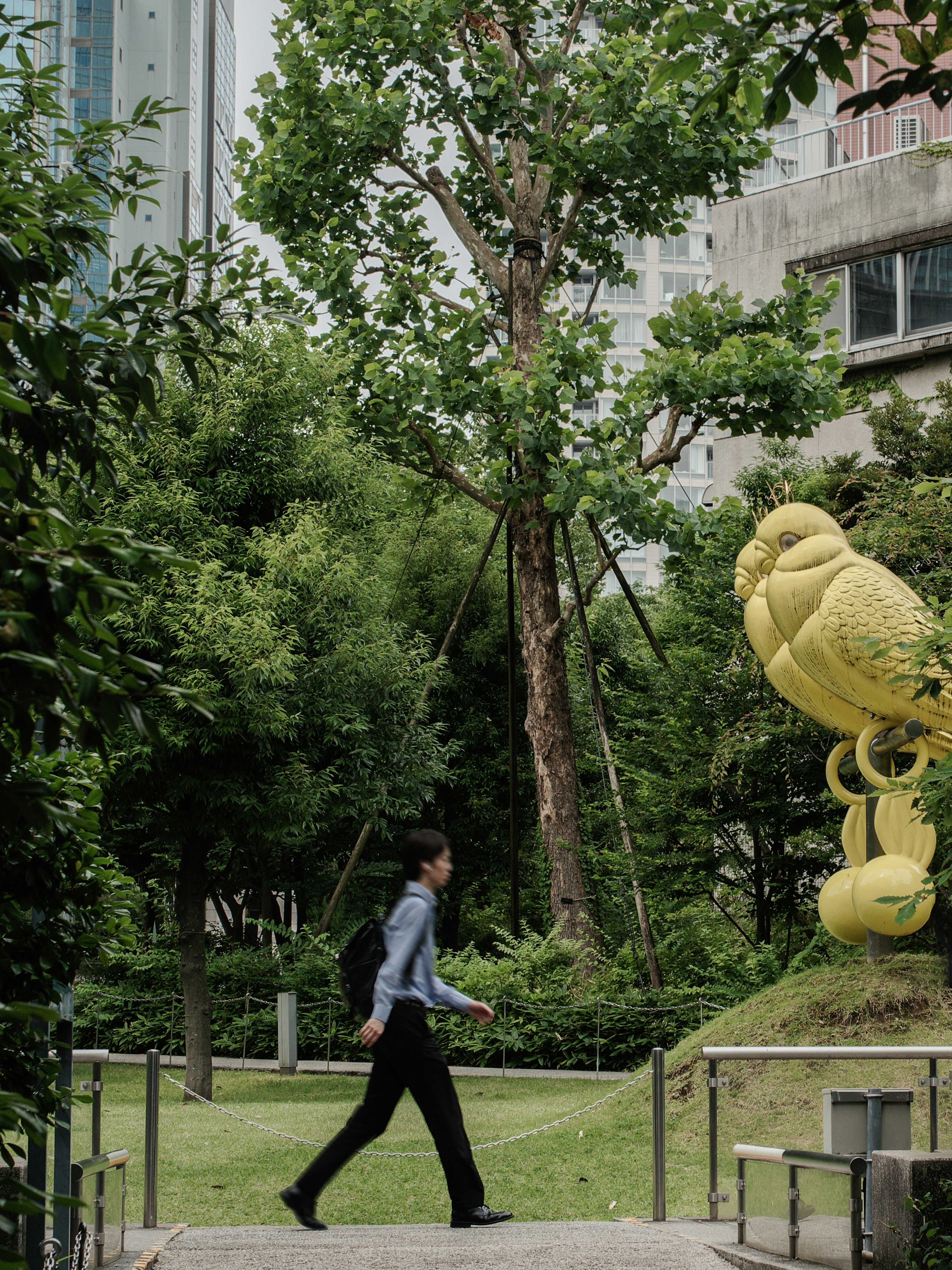 Homme d'affaires marchant dans un parc vert avec une sculpture jaune