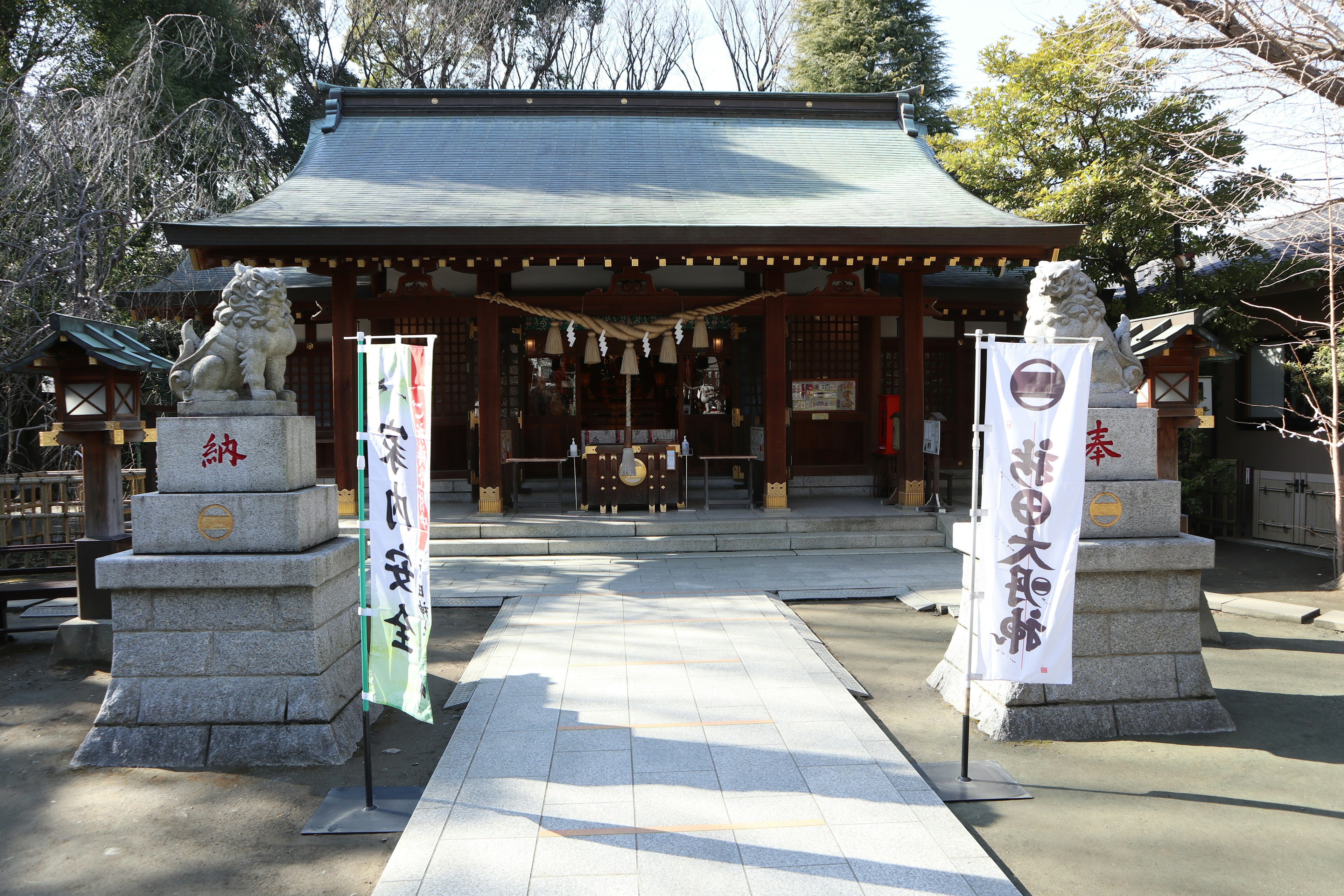 Entrance of a shrine with guardian lions and banners on both sides