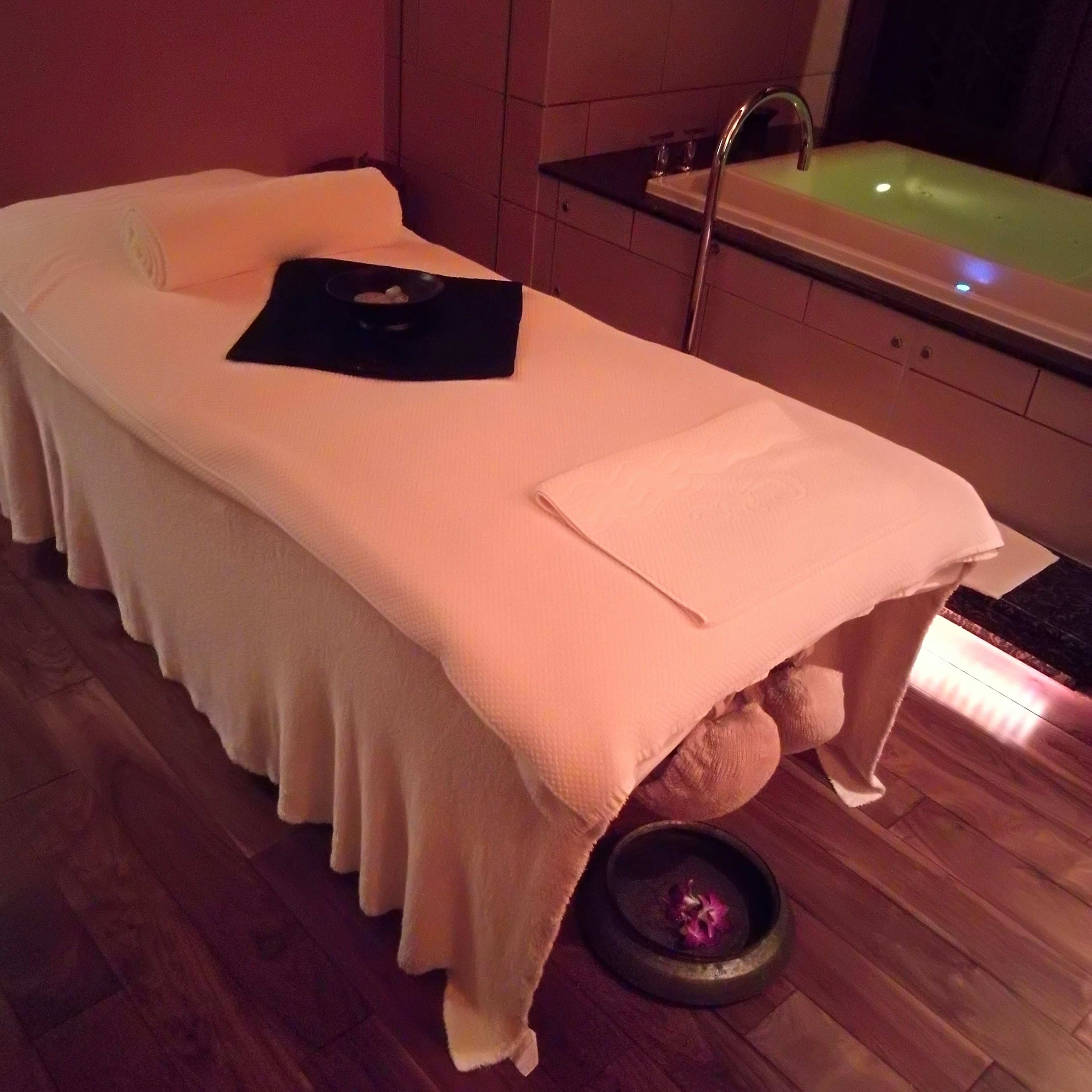 Spa massage table with a bathtub in the background