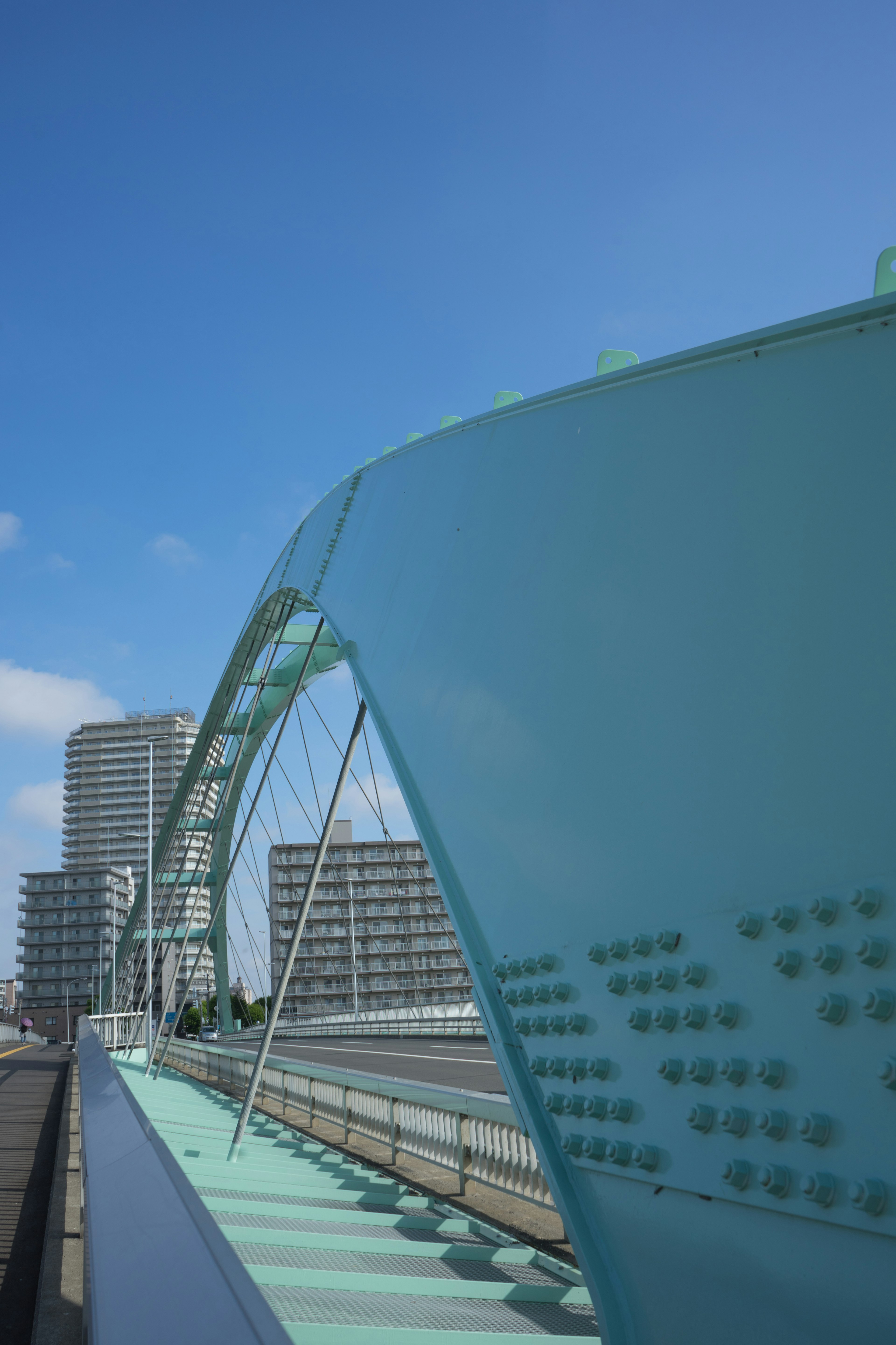 Vista de un puente en arco azul con edificios altos cercanos