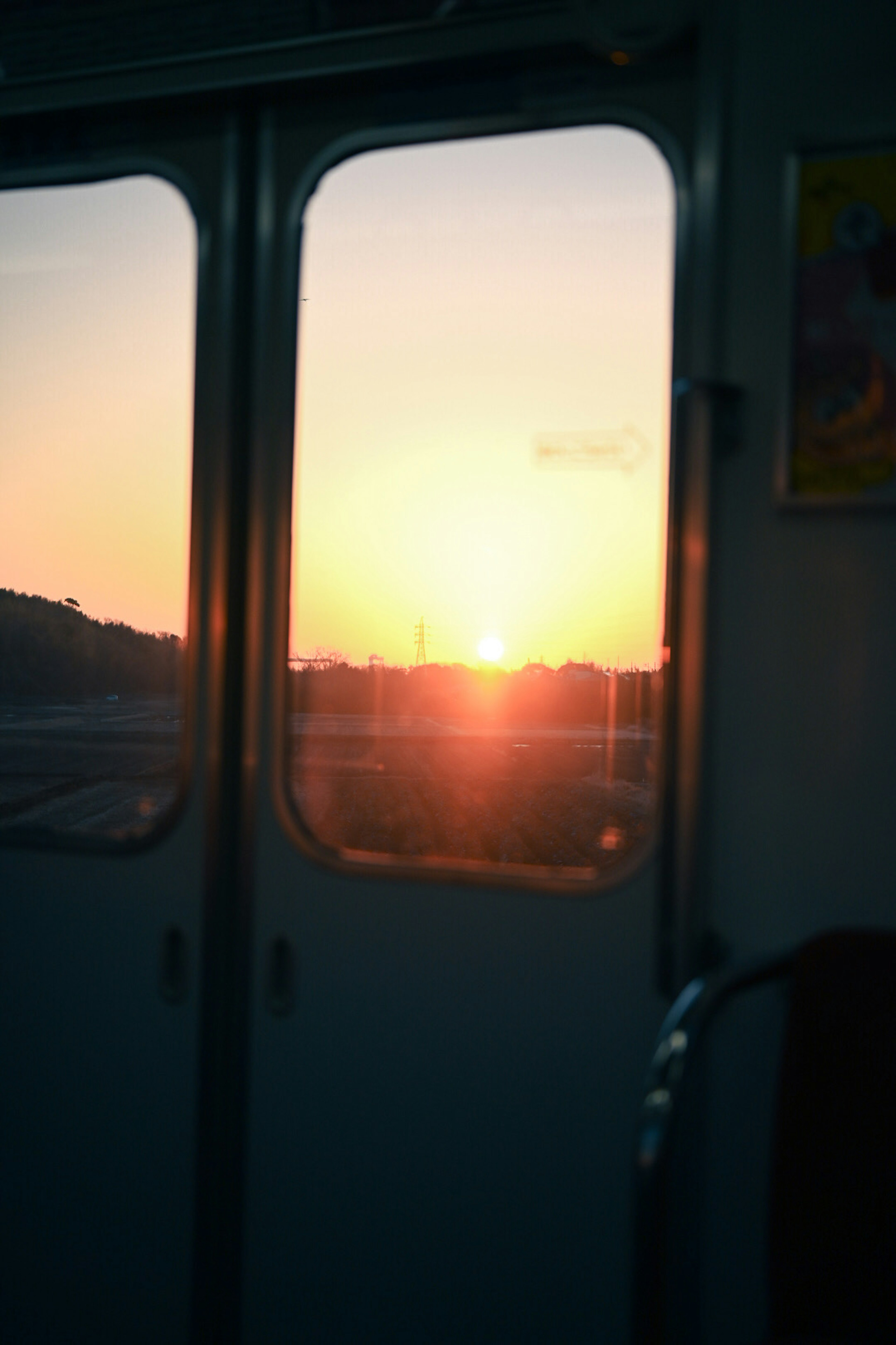 Sunset view from a train window with silhouettes of hills