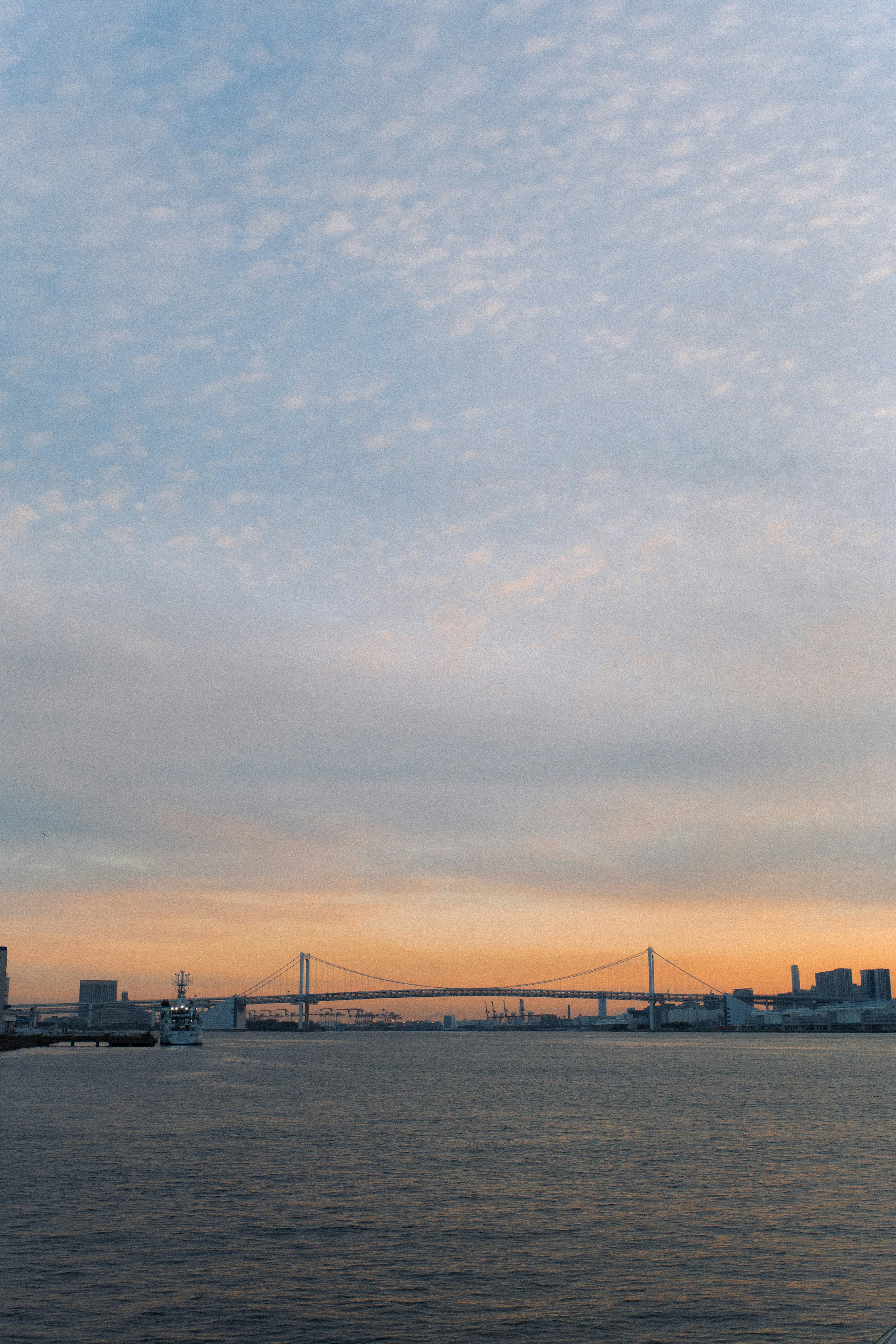 水面に映る夕焼けと橋のシルエットが美しい河川の風景