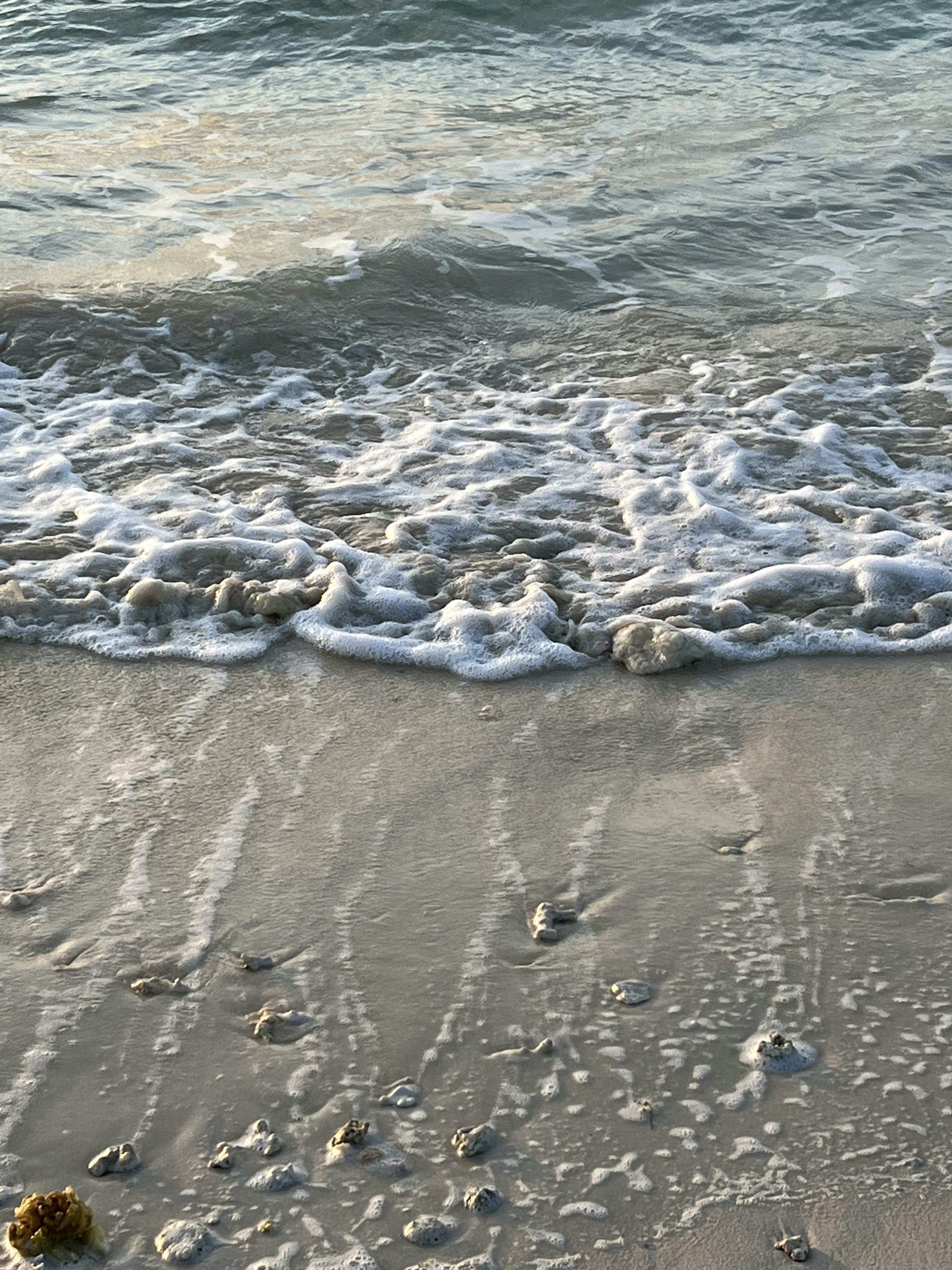 Wellen brechen sanft an einem Sandstrand