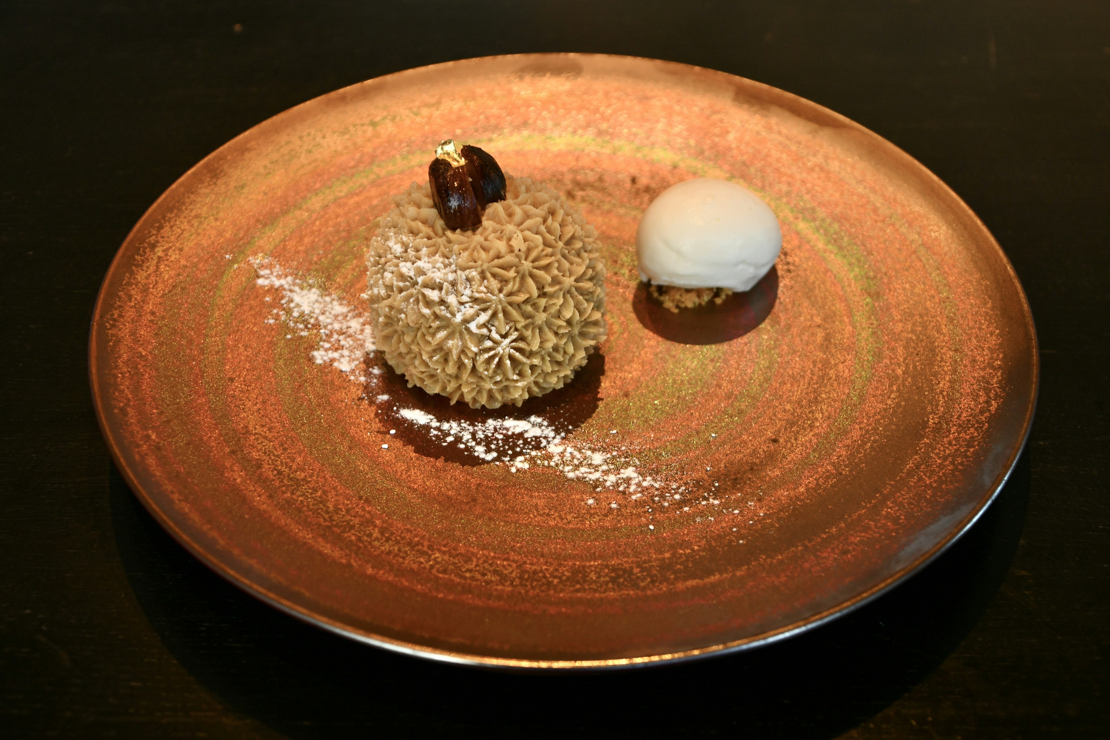 Dessert auf einem Teller mit cremigem Eis und fluffigem Kuchen, dekoriert mit Puderzucker