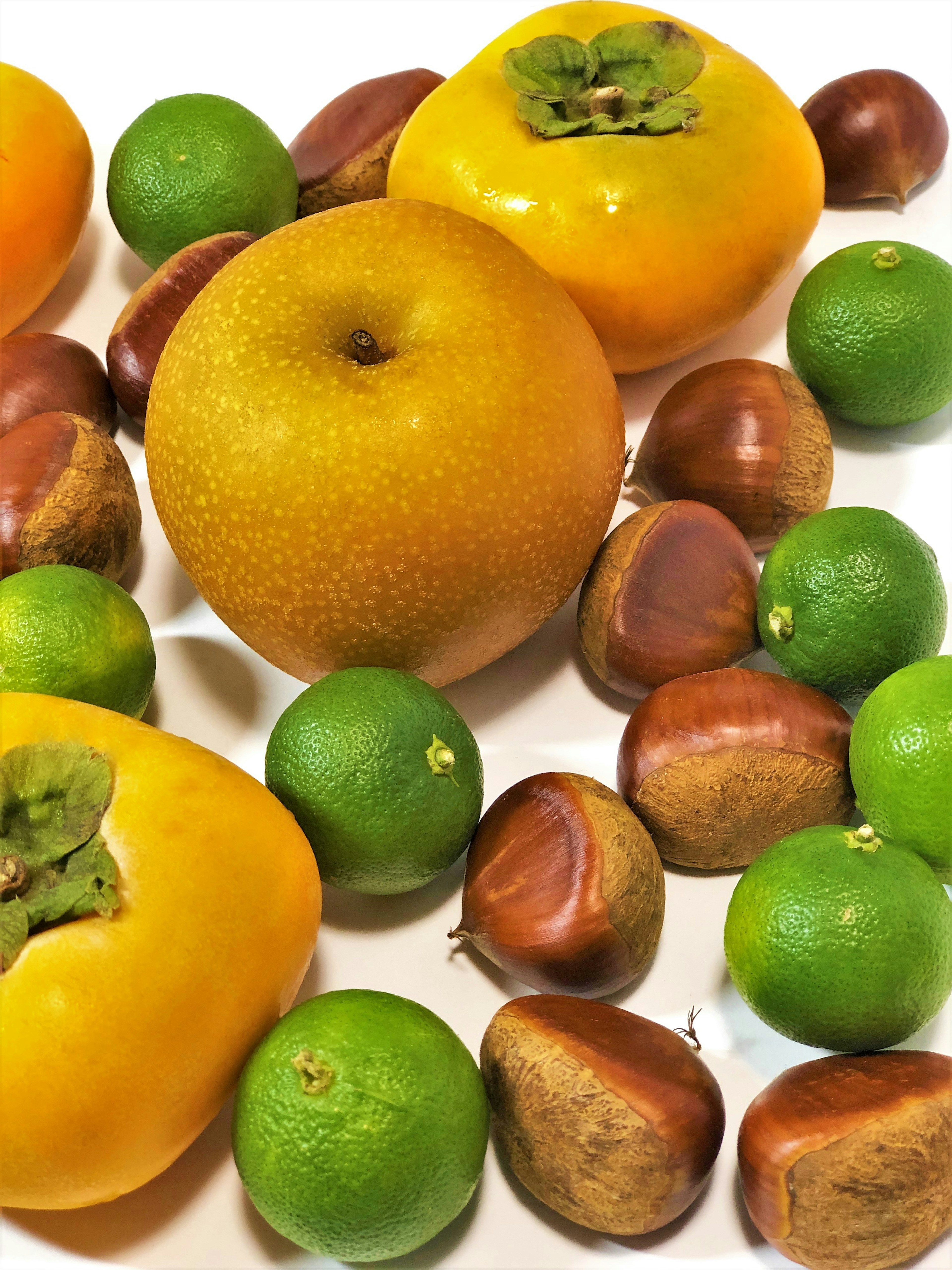 Colorful arrangement of fruits and nuts including persimmons and chestnuts