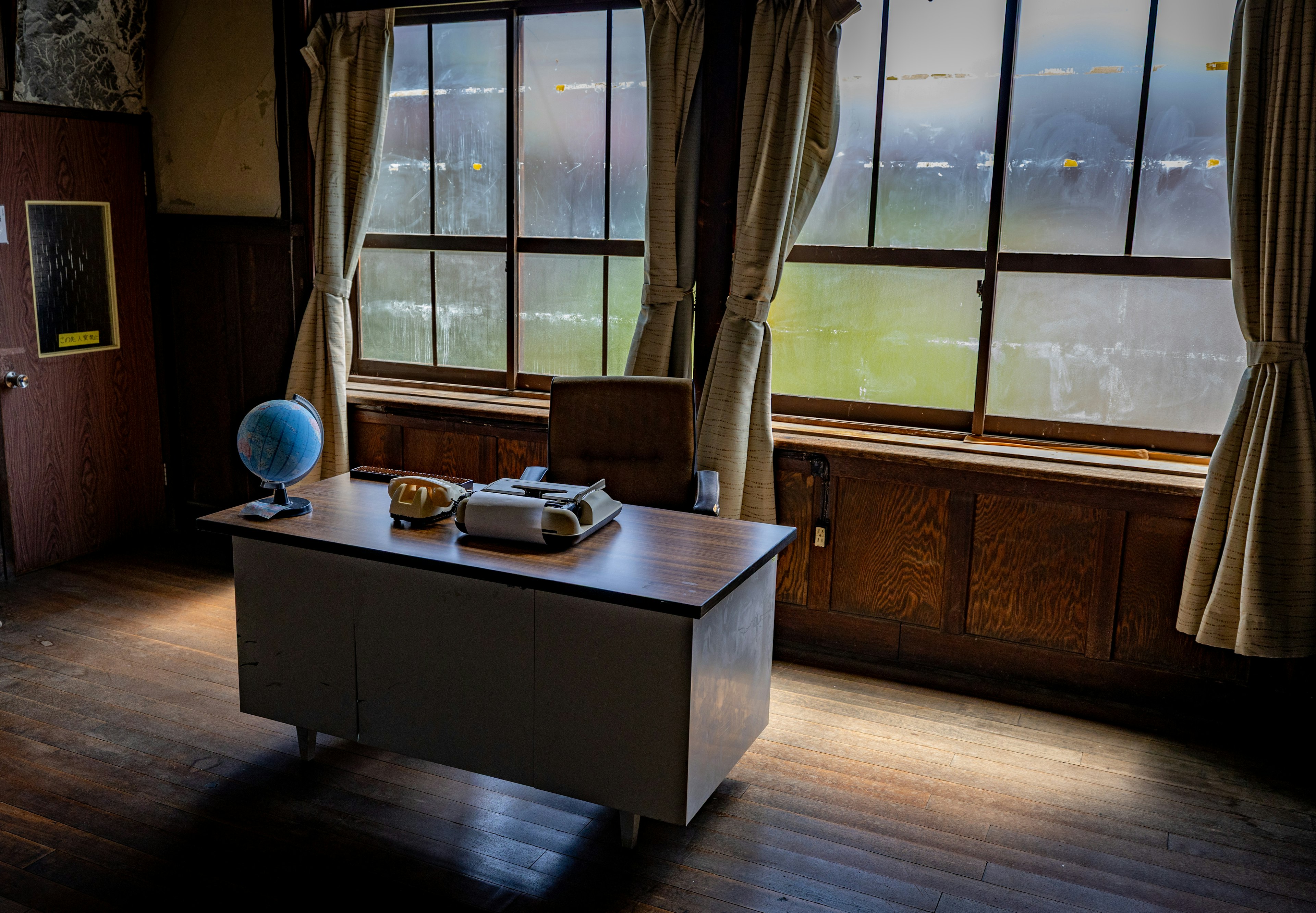 Intérieur d'un bureau avec de grandes fenêtres comprenant un bureau et une chaise un globe et des petits objets sur le bureau