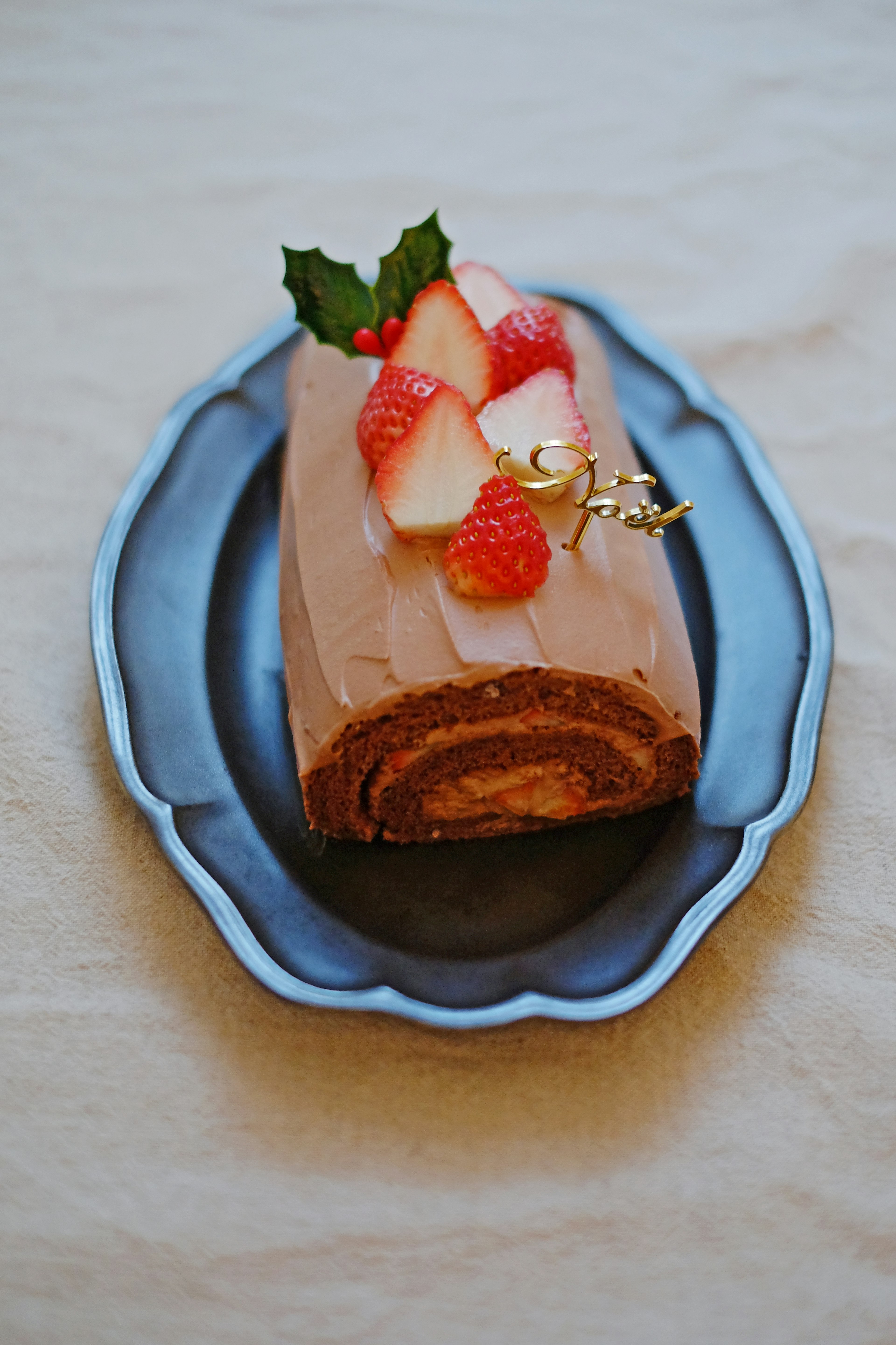 Torta arrotolata al cioccolato guarnita con fragole e foglie di menta