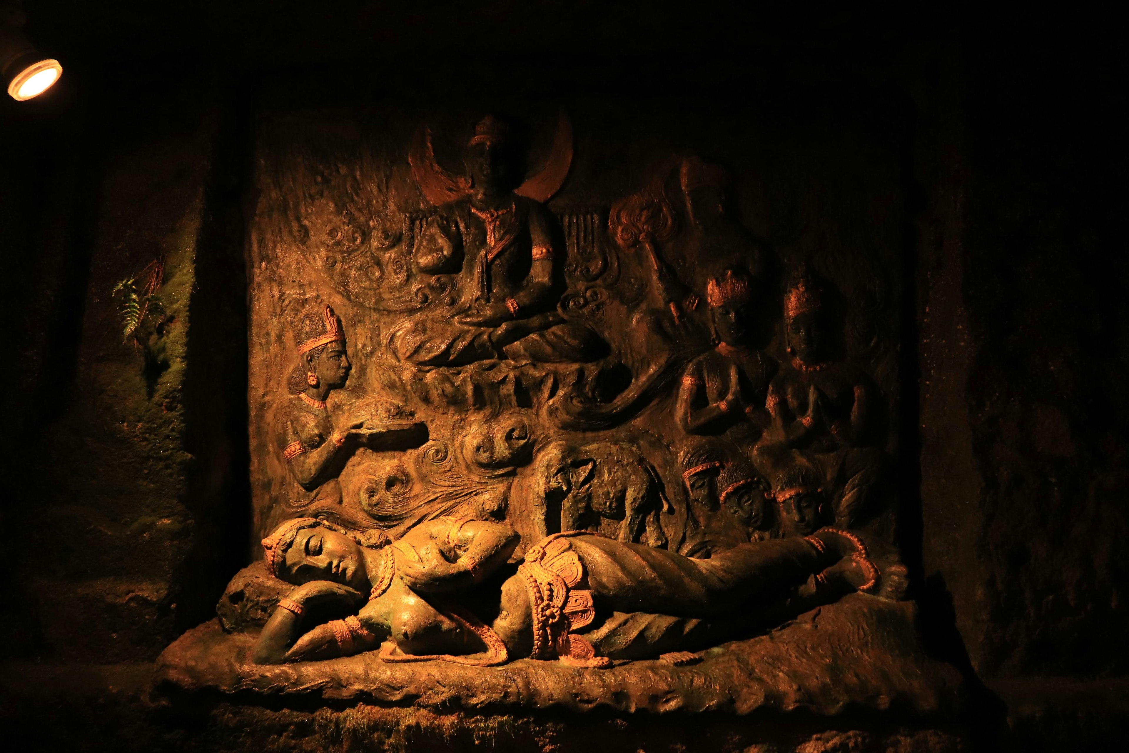 Relief batu dari Buddha yang berbaring dengan figur lain di latar belakang