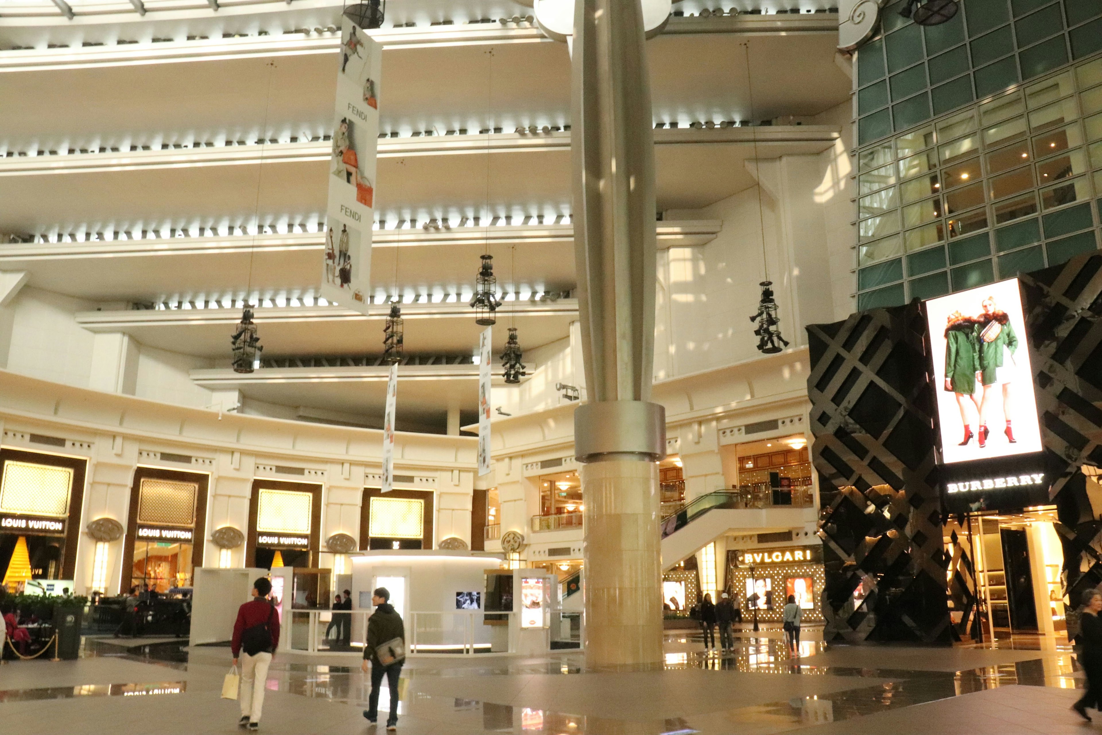 Intérieur spacieux d'un centre commercial avec des murs blancs et de hauts plafonds, un grand pilier central