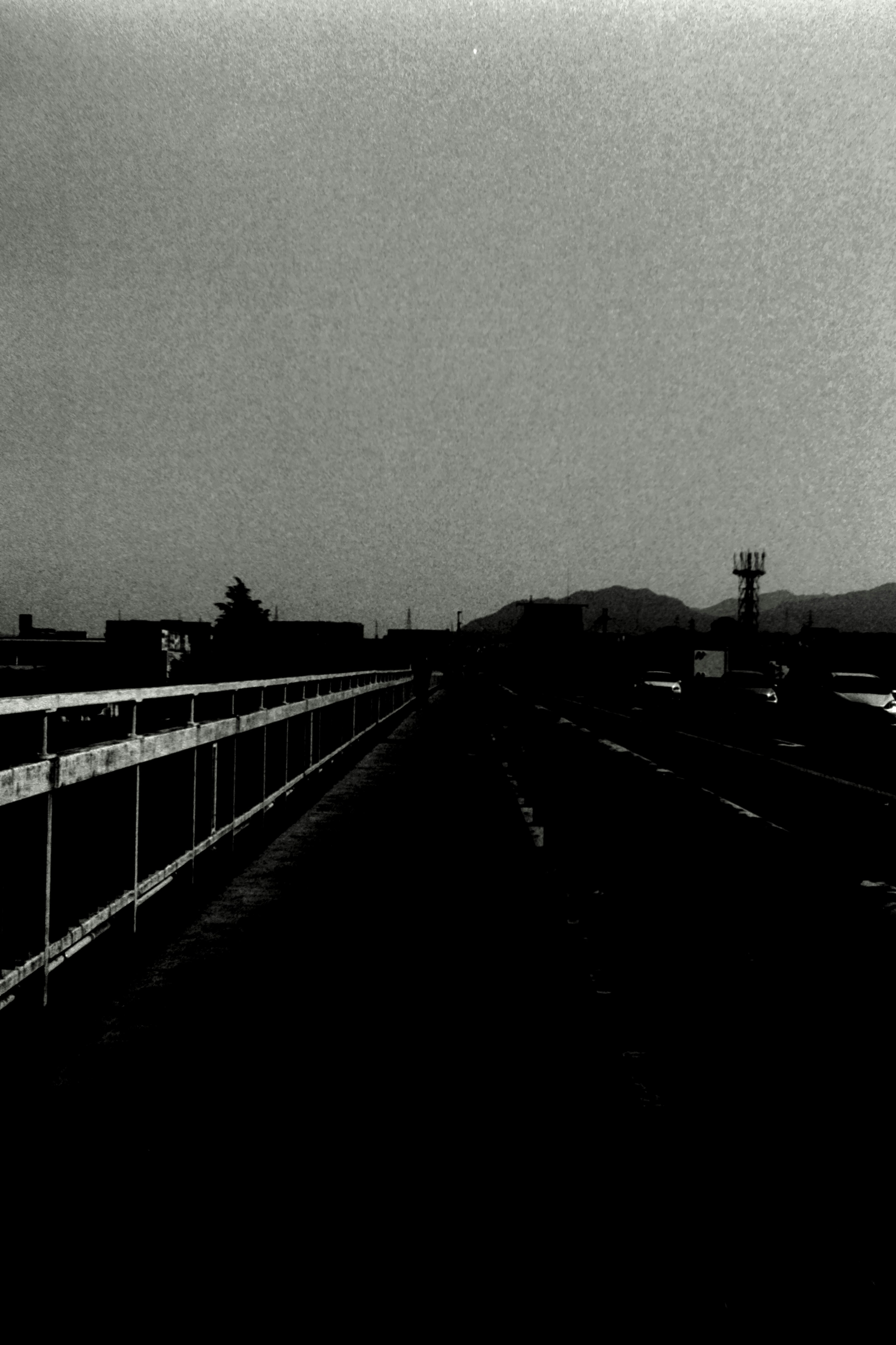 Vista en blanco y negro de un puente con montañas a lo lejos