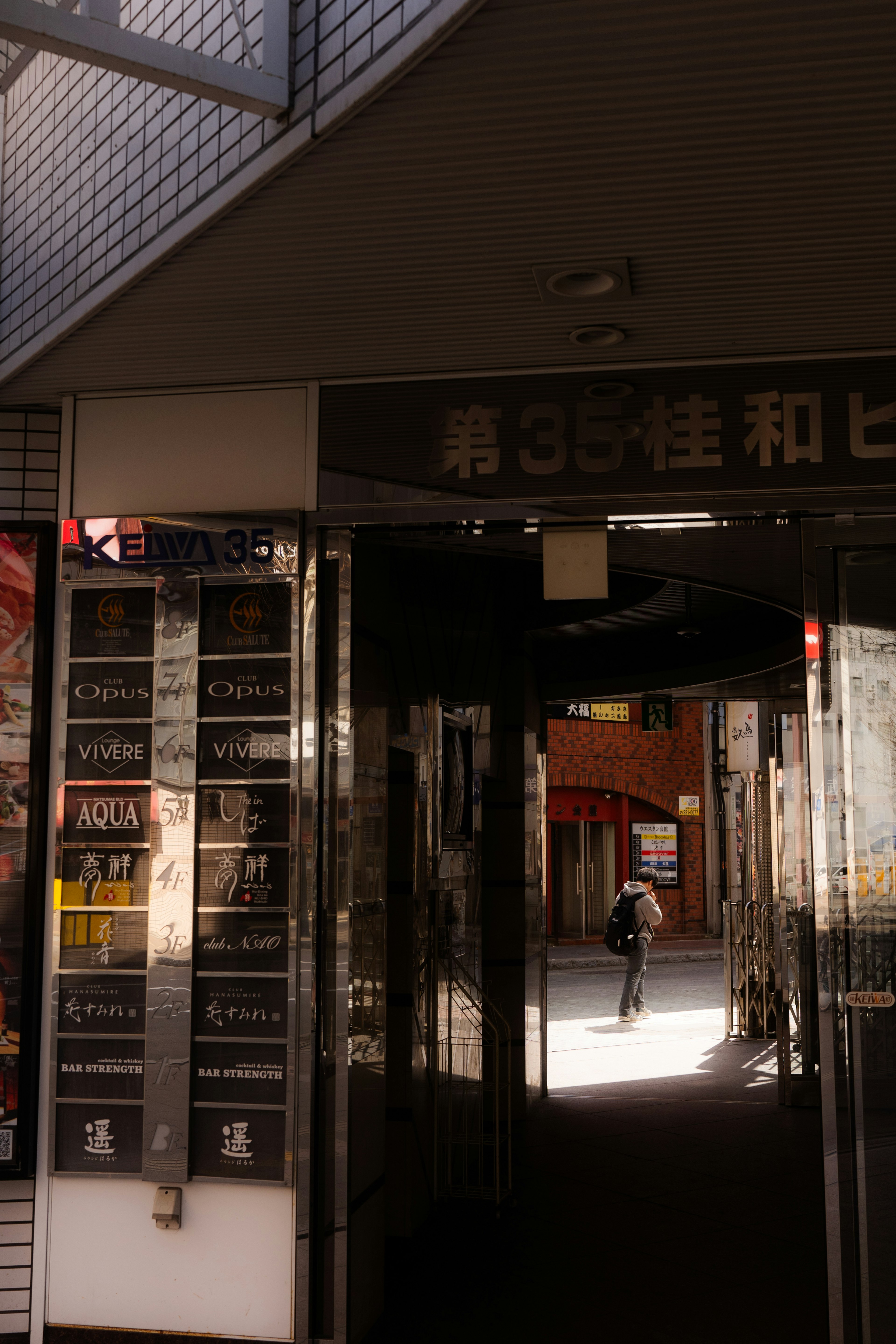 Entrée d'un bâtiment commercial faisant face à une rue lumineuse avec une personne marchant