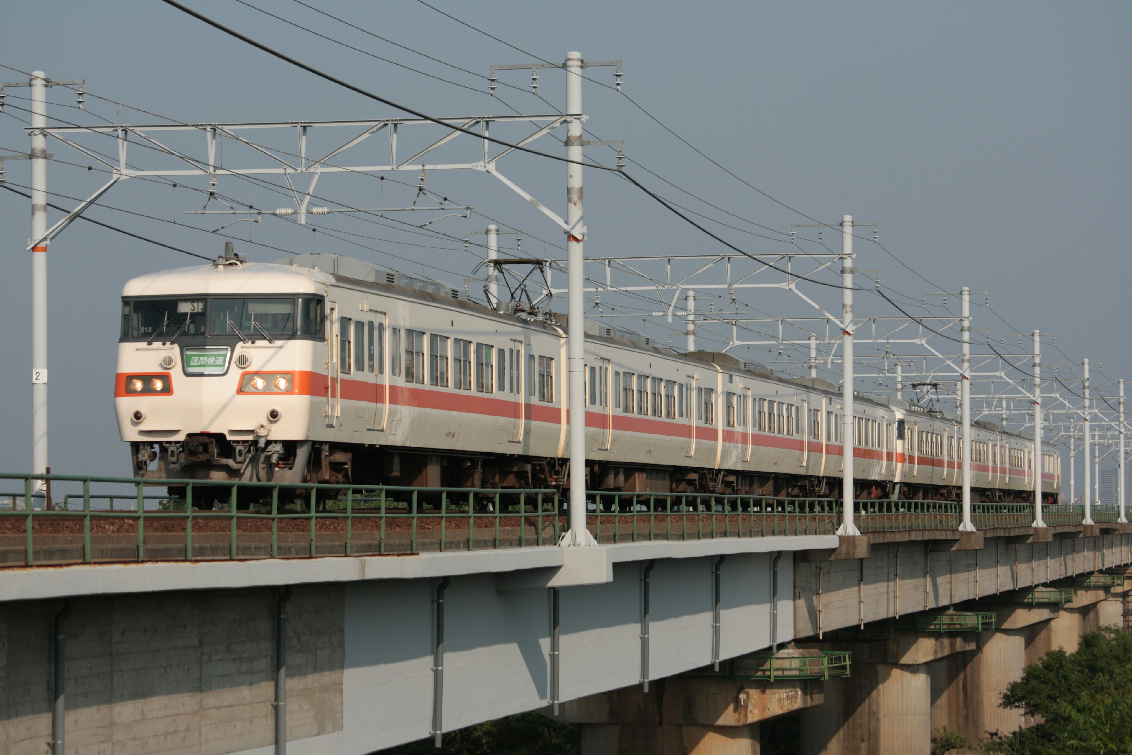 A white train traveling on an elevated bridge