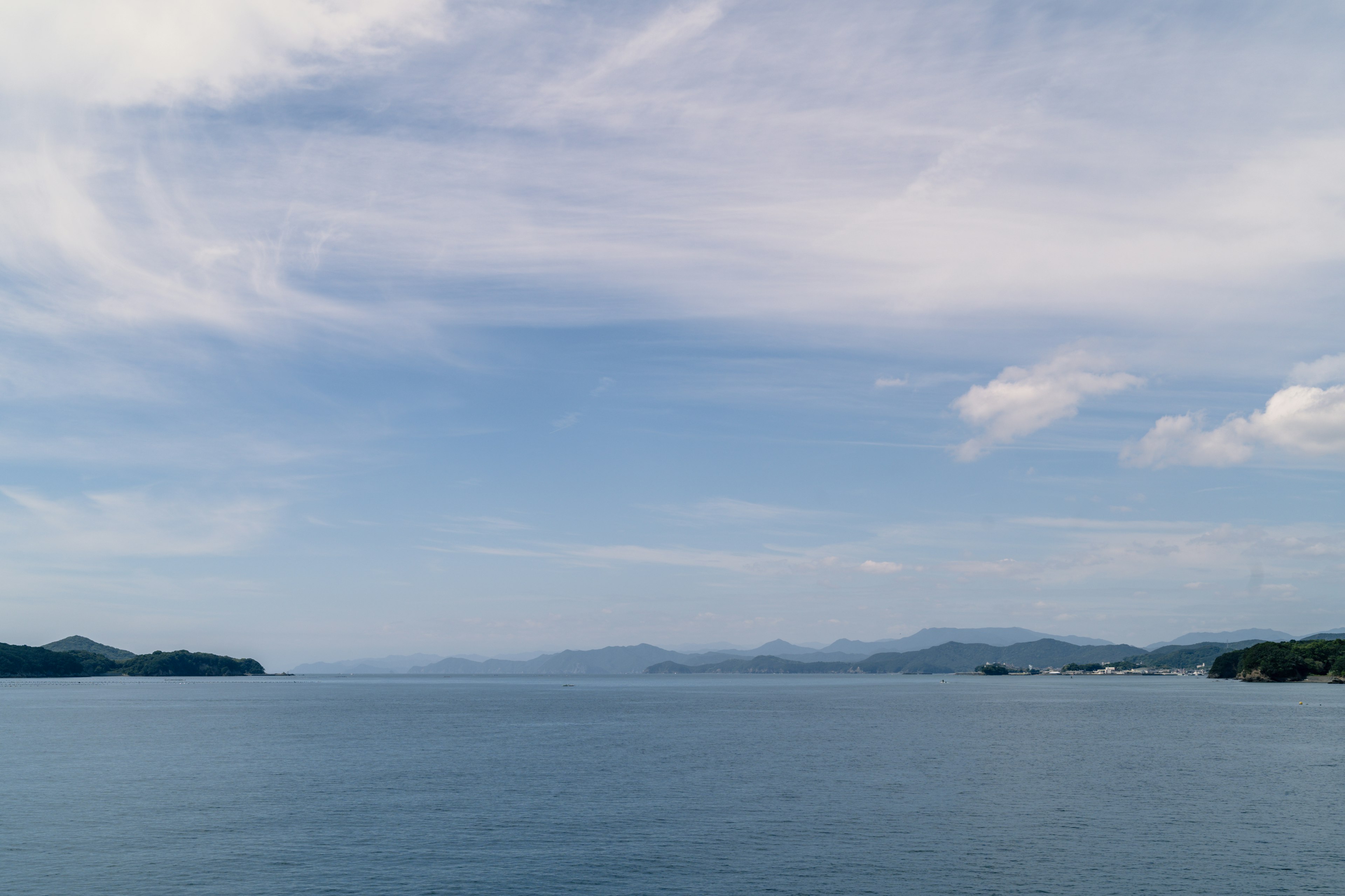 Amplio paisaje de mar y cielo azul con montañas a lo lejos