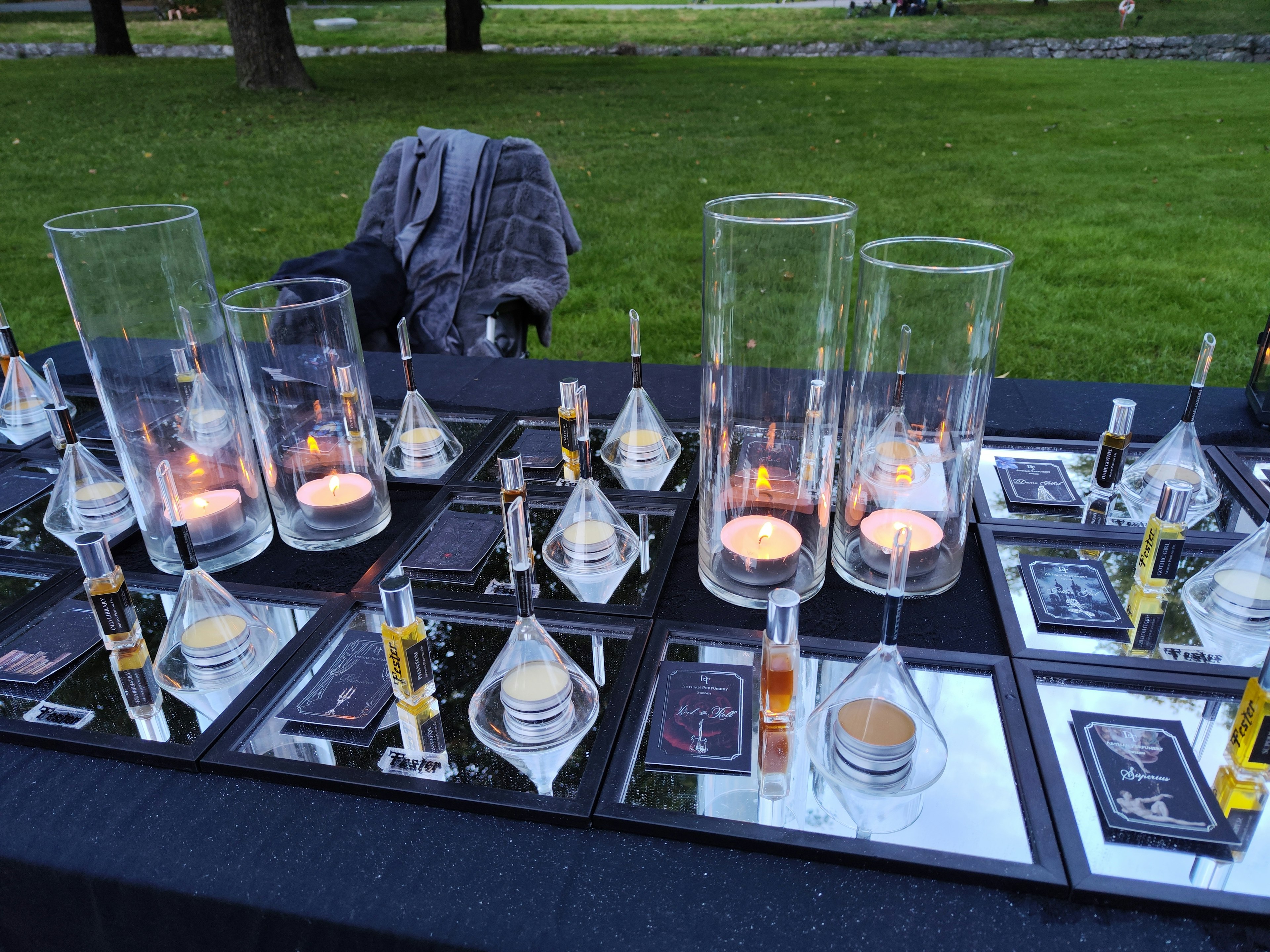 Table displaying various perfume bottles and candles in transparent containers