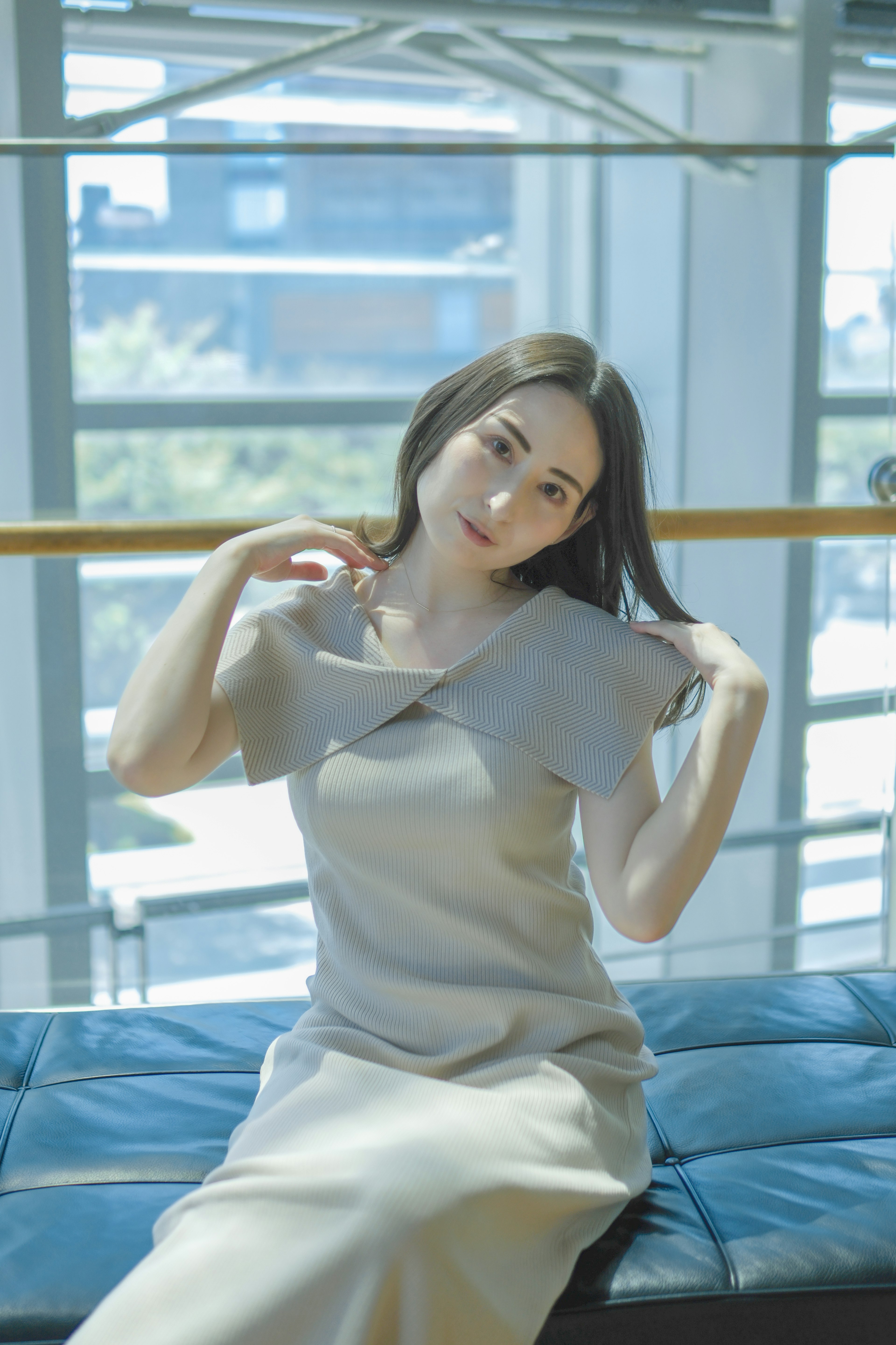 Una mujer posando junto a una ventana brillante