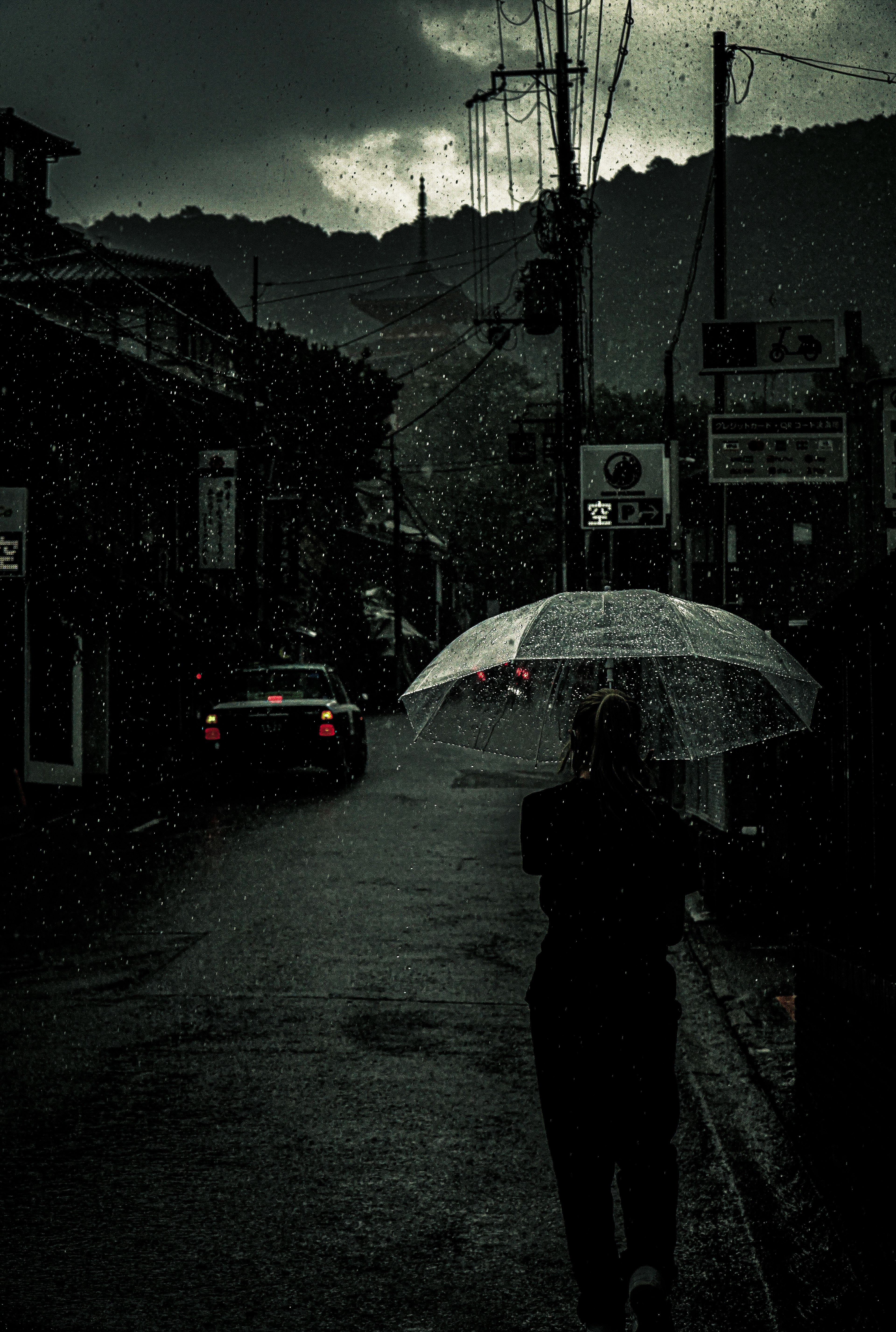 Persona caminando con paraguas bajo la lluvia y escena de calle oscura