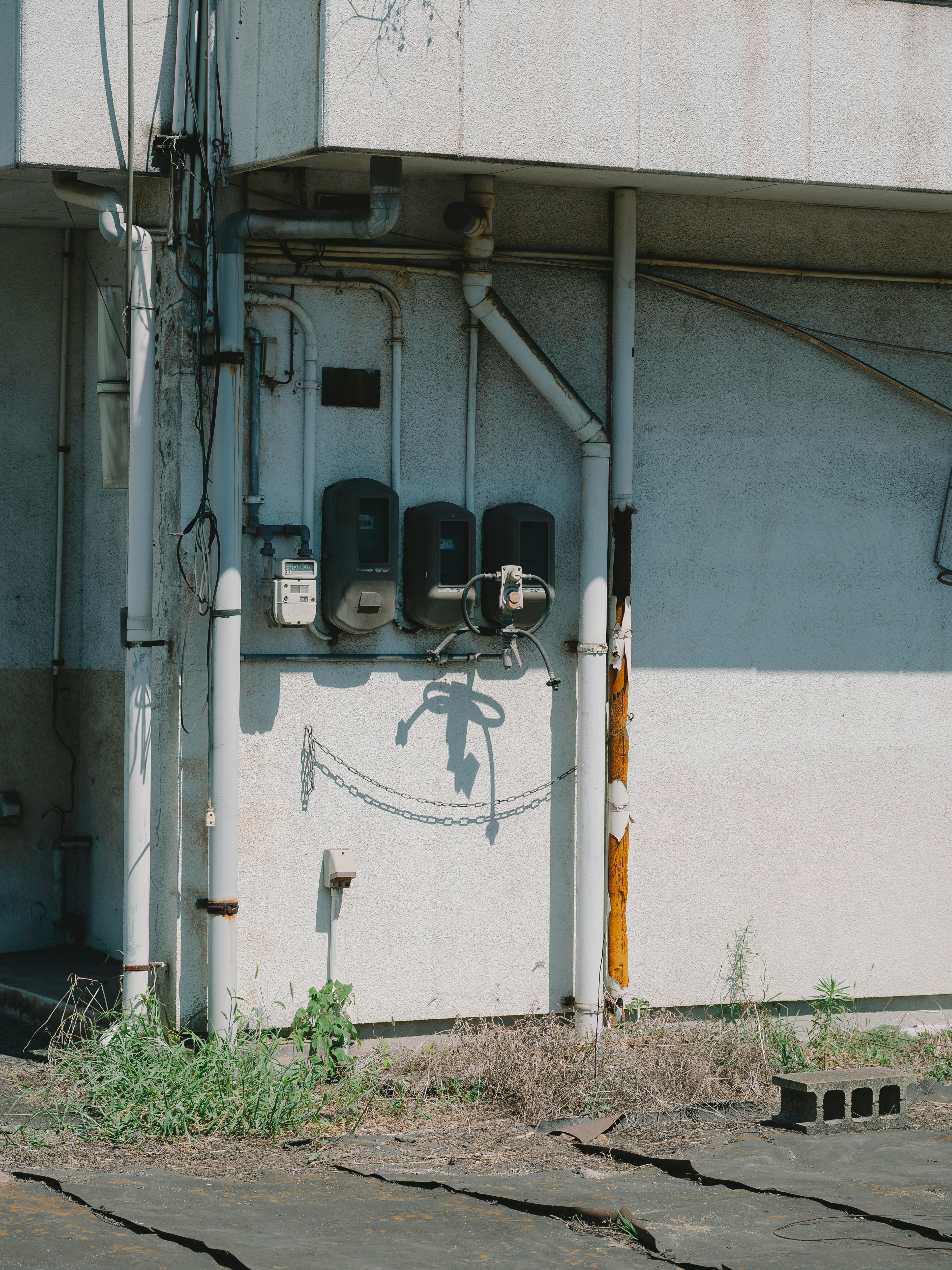 Detail of electric meters and piping on the exterior wall of an old building