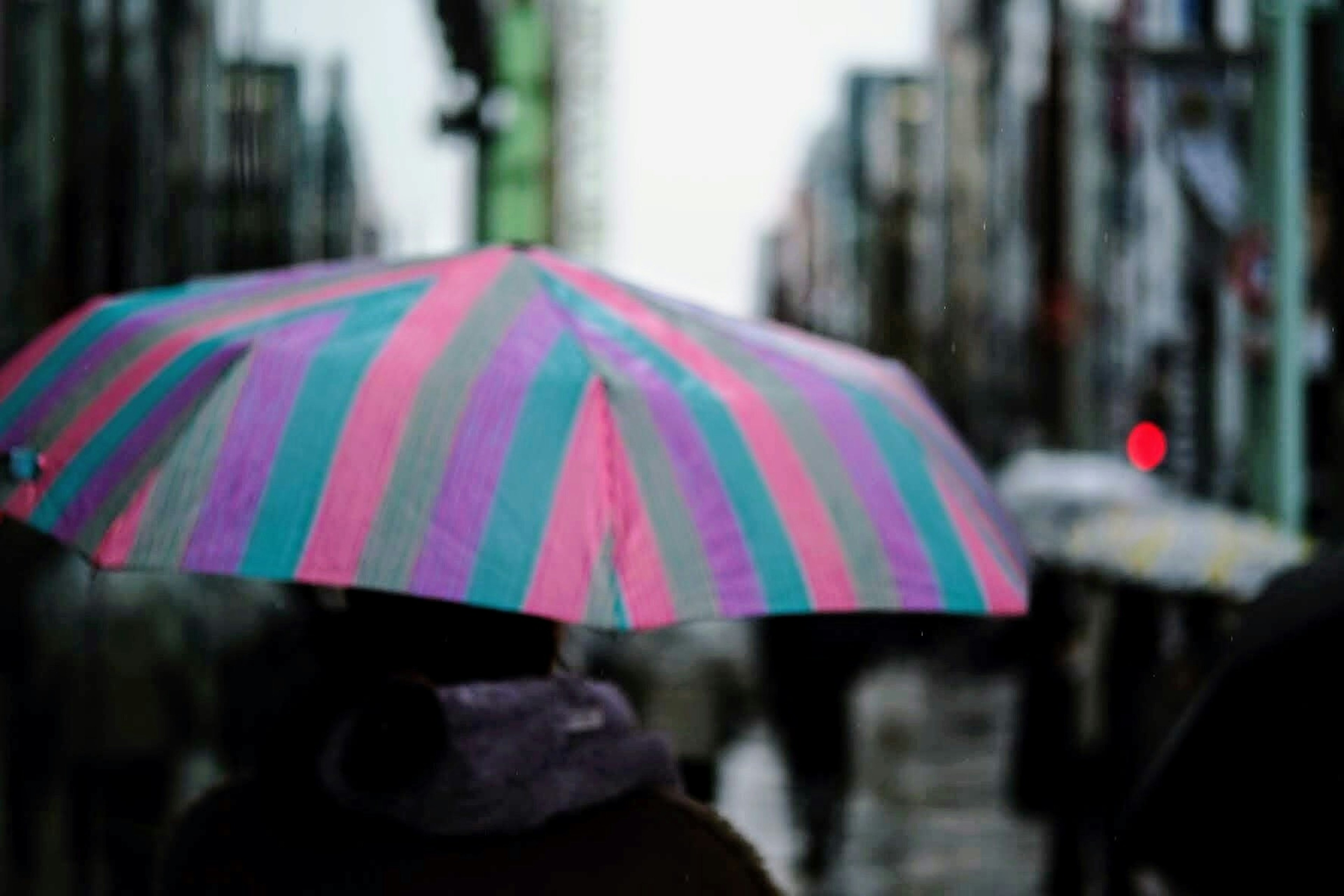 Personne tenant un parapluie rayé coloré avec une rue de ville en arrière-plan