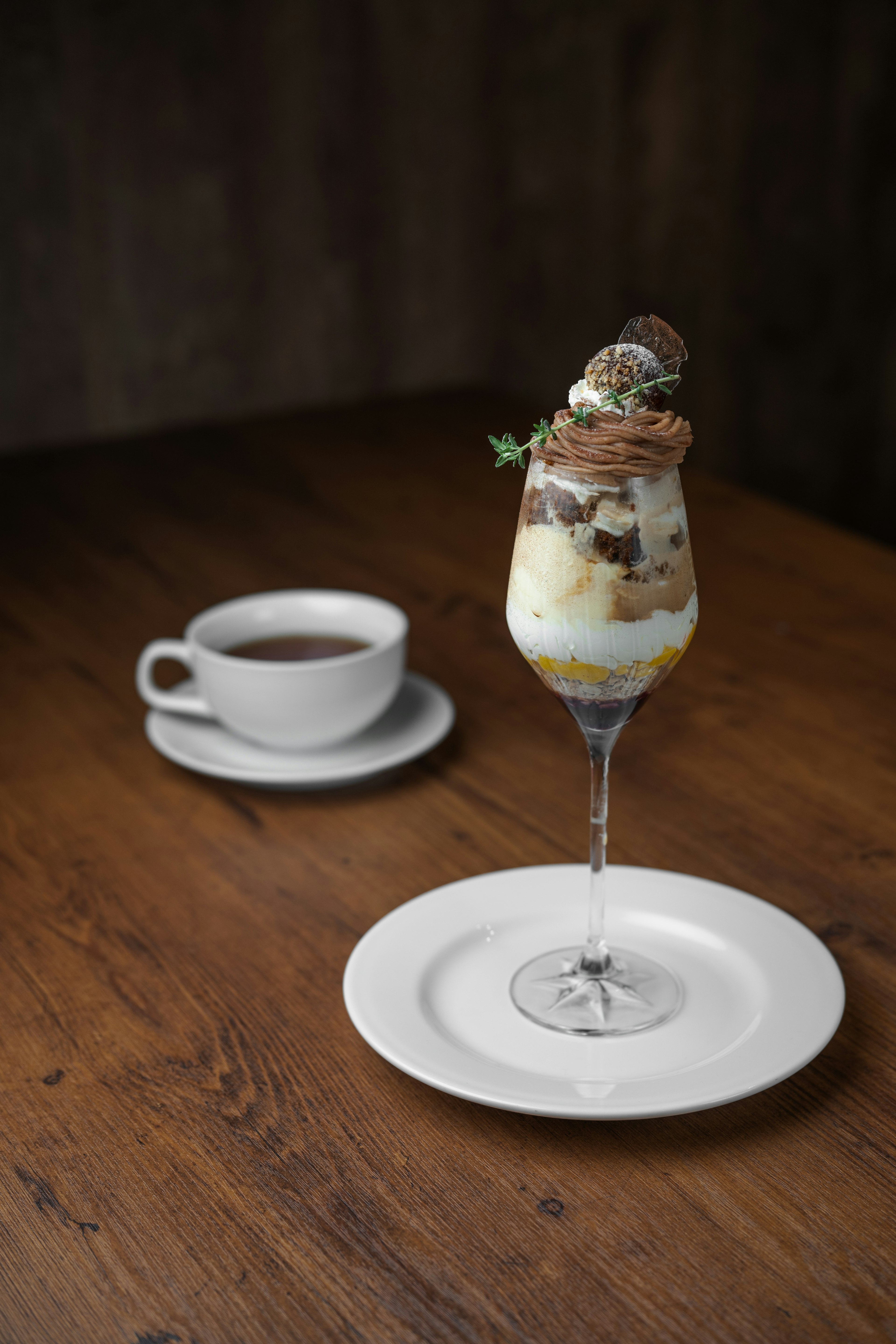 Elegante bicchiere di dessert ripieno di parfait e una tazza di caffè