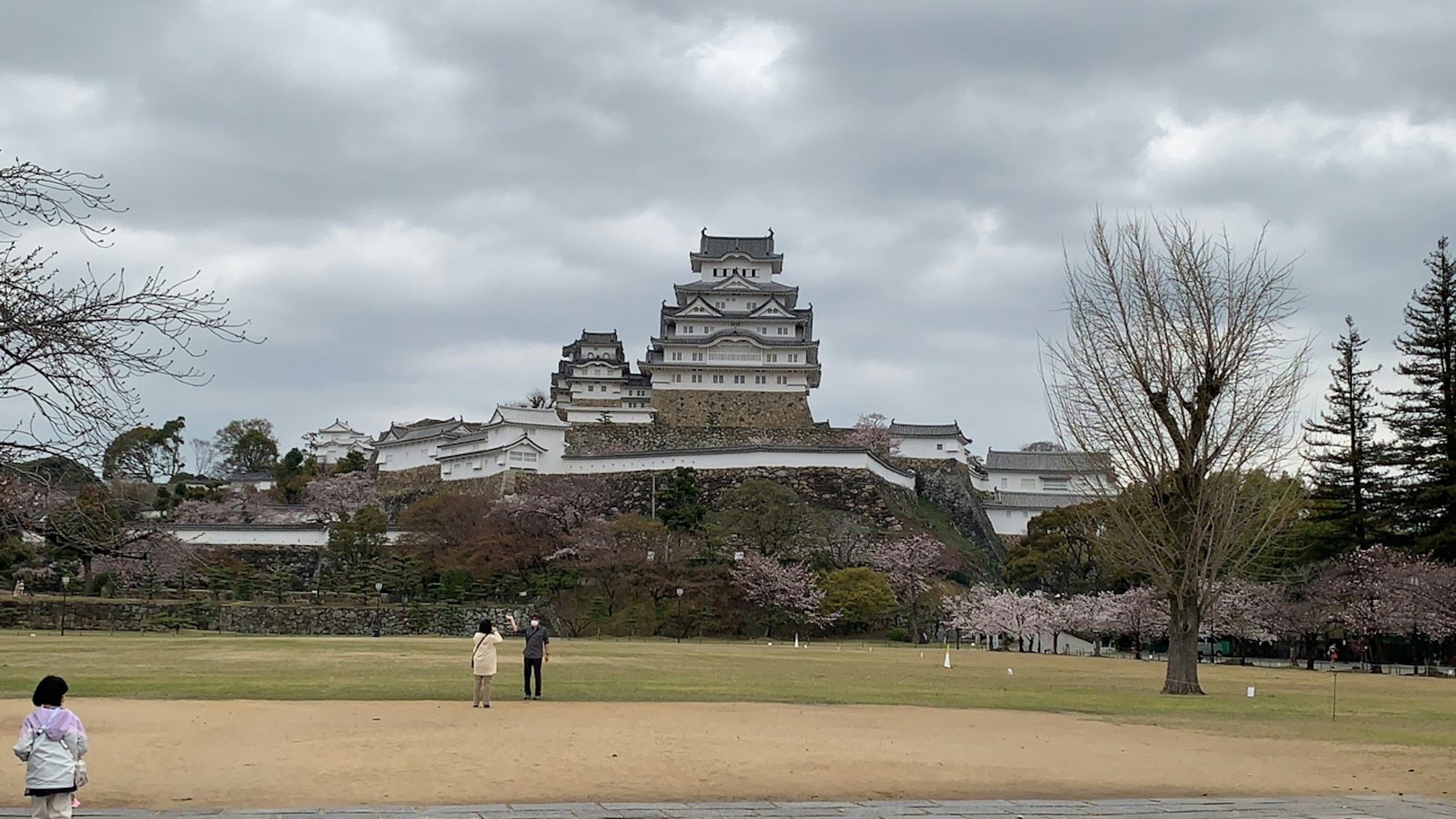 Vista del castello di Himeji con un ampio parco in primo piano e persone presenti