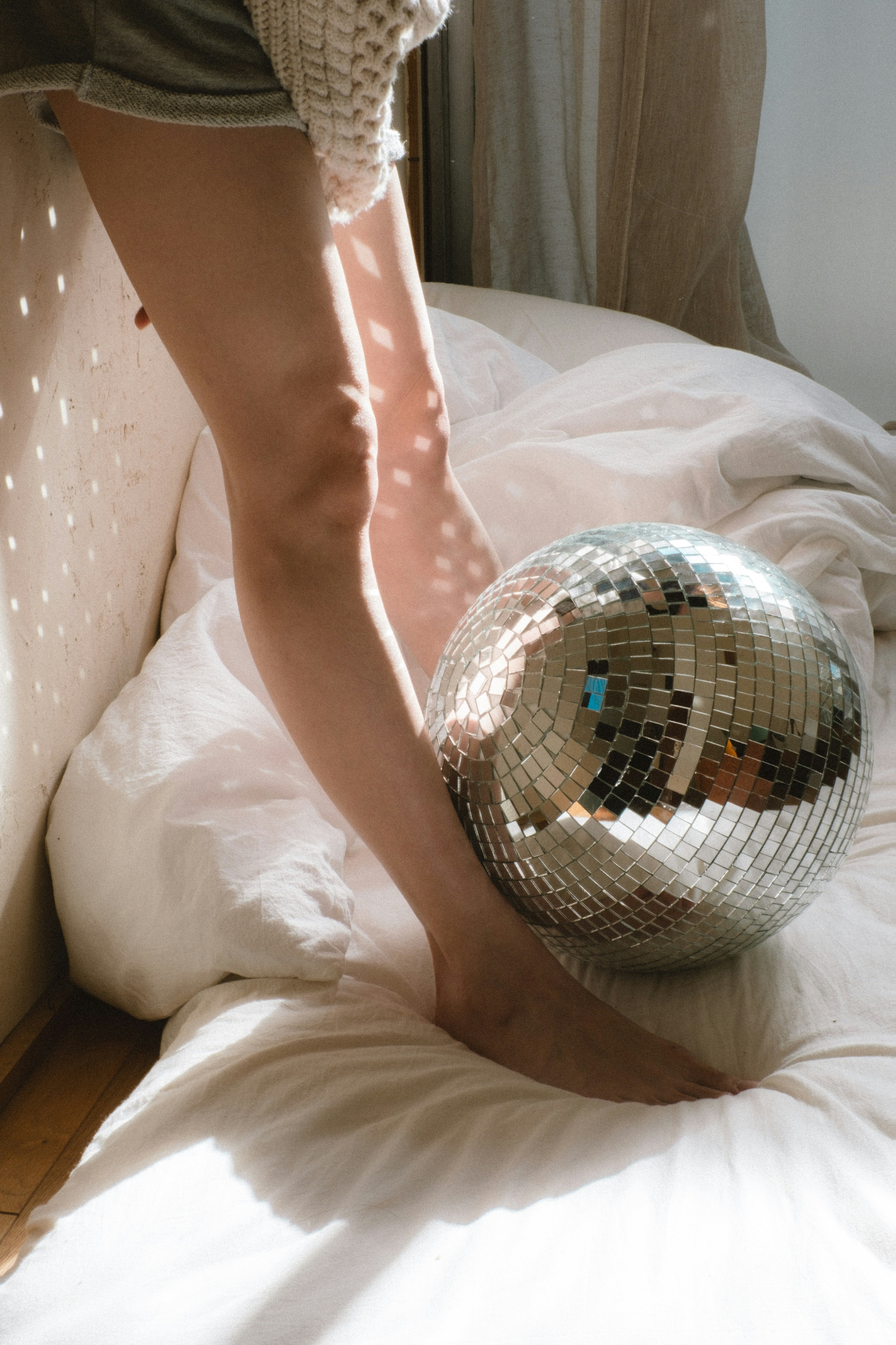 Une jambe de femme à côté d'une boule disco sur un lit