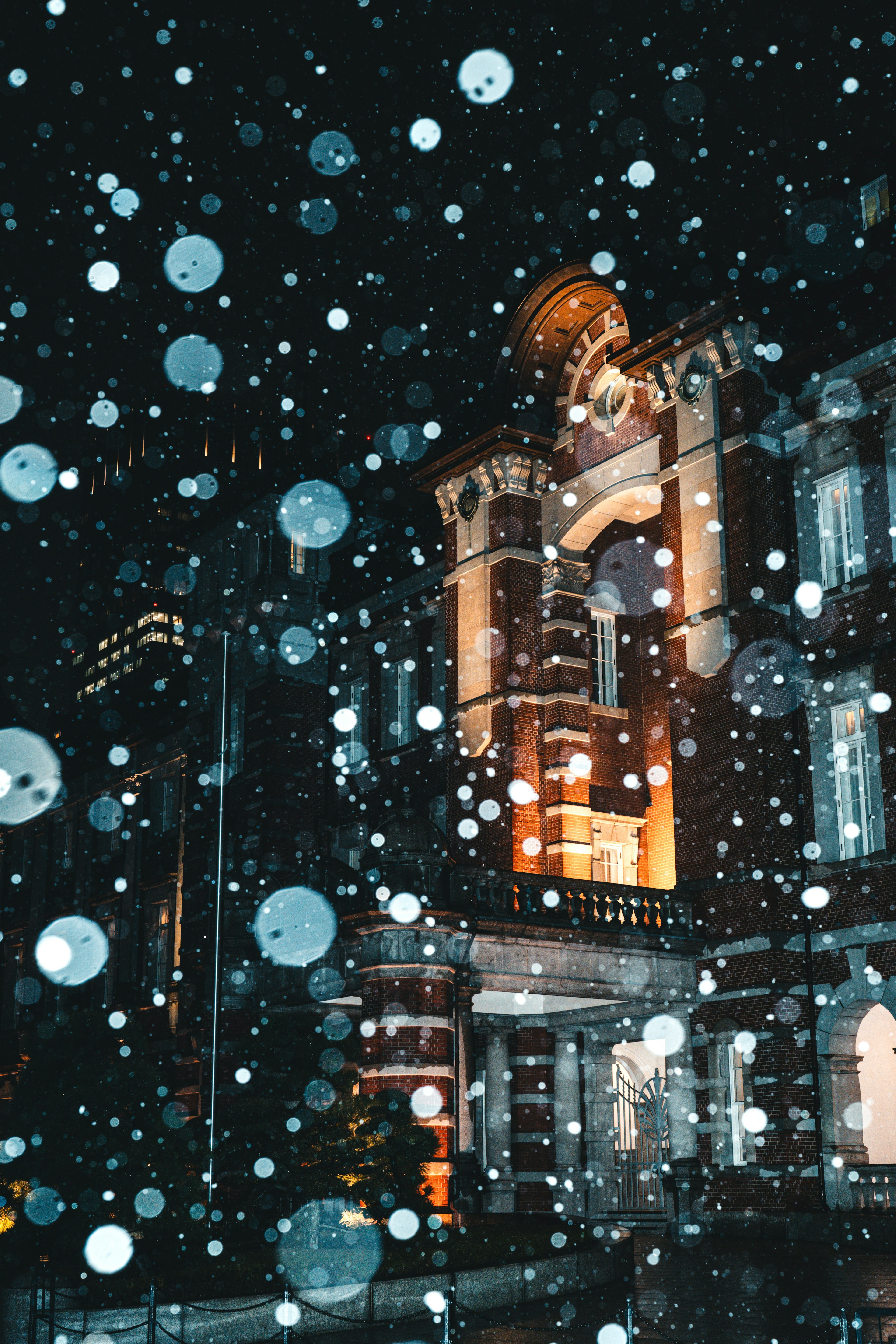 Un bell'edificio illuminato di notte con fiocchi di neve che cadono