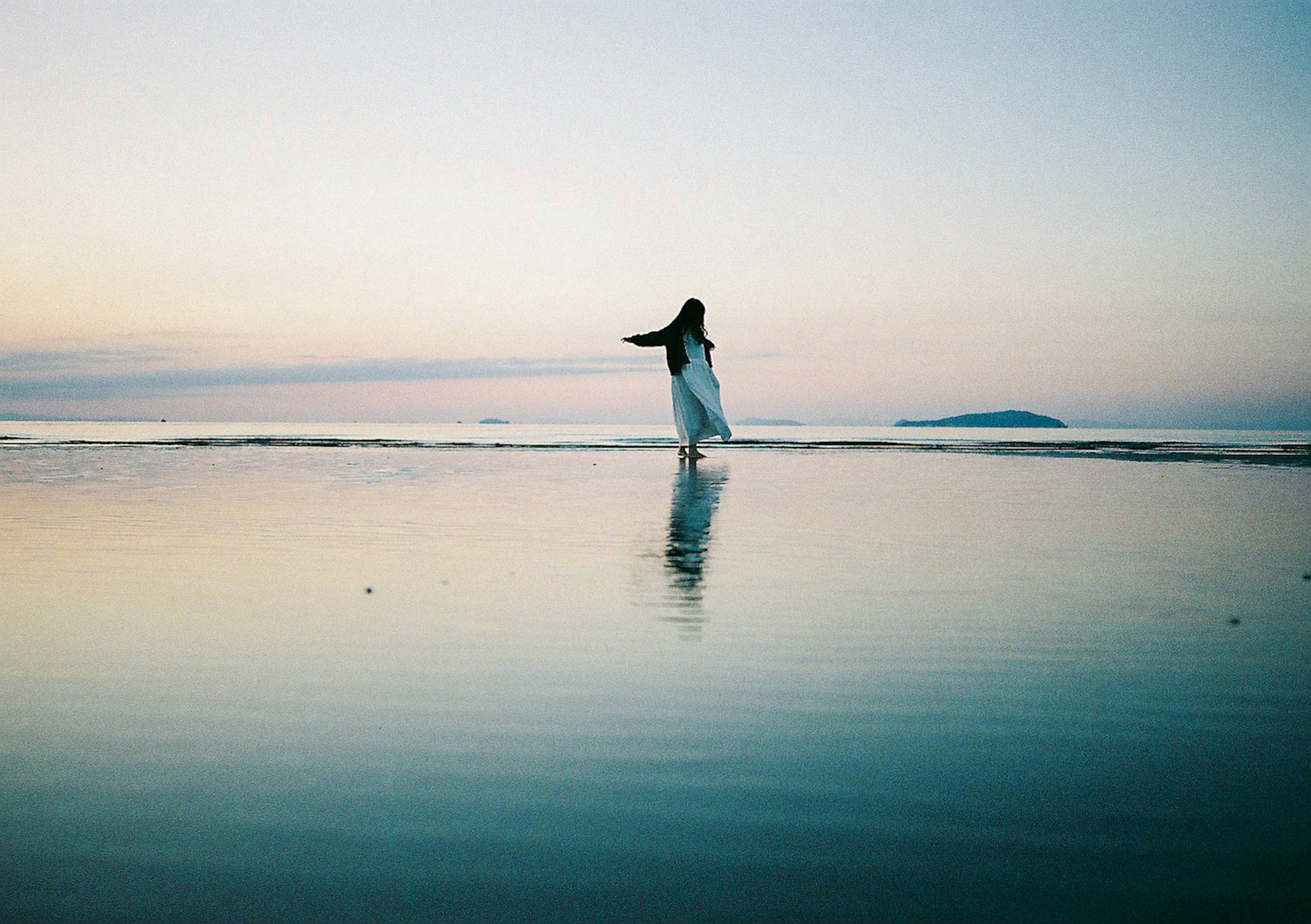 Una donna in abito bianco che sta al mare