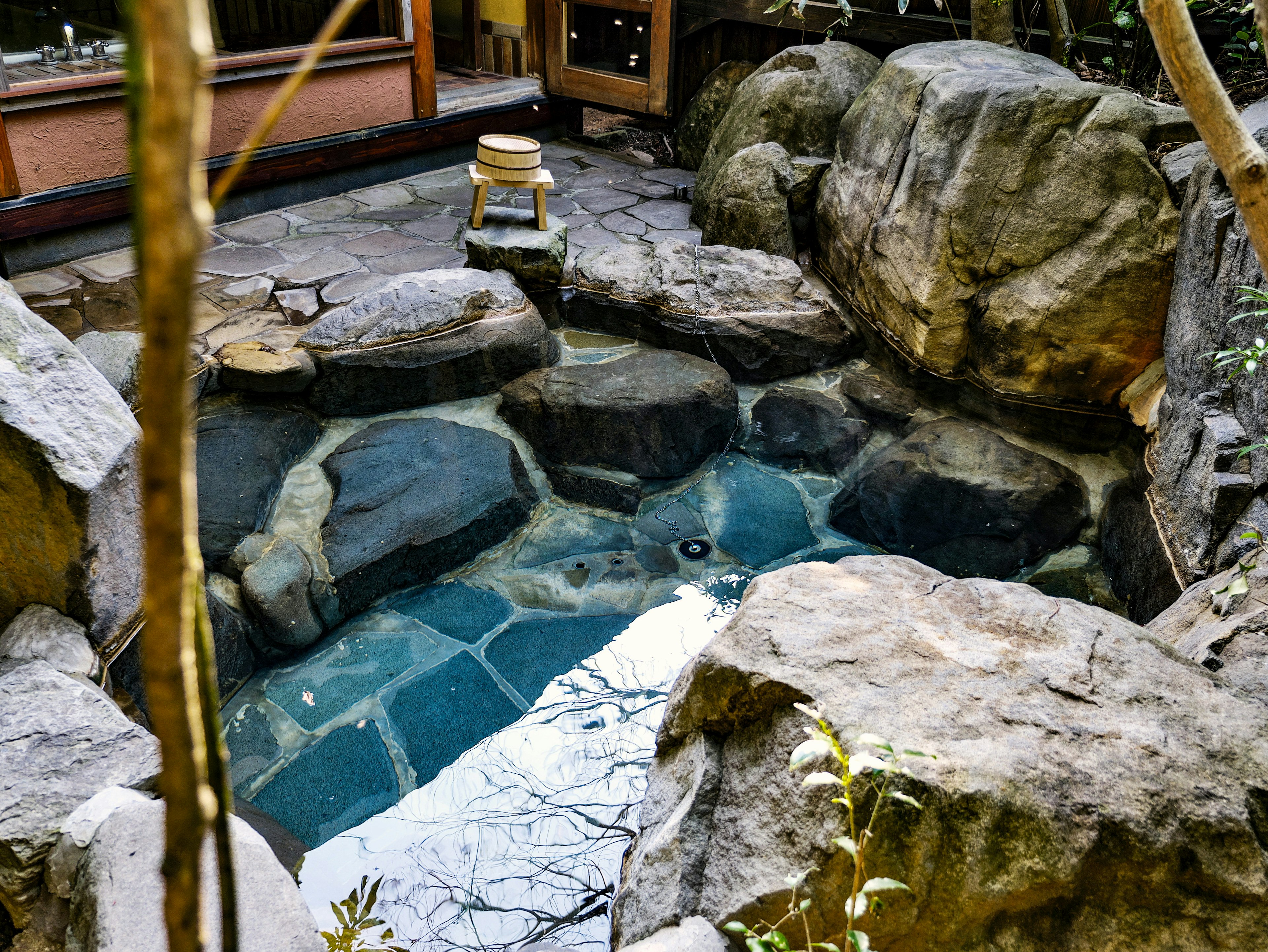 Natural hot spring-like pond surrounded by large stones and green plants