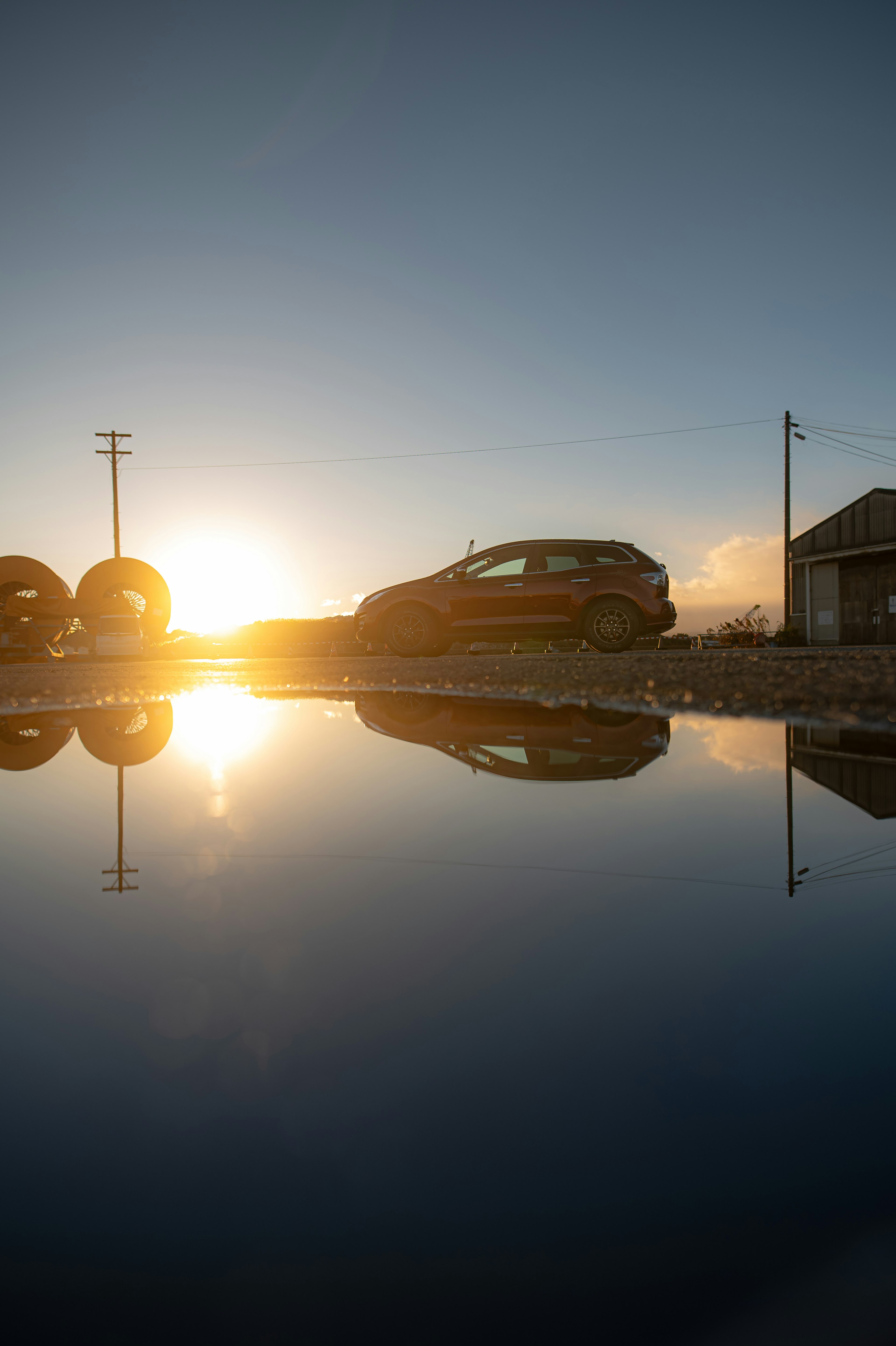 Auto accanto a una pozzanghera che riflette il tramonto