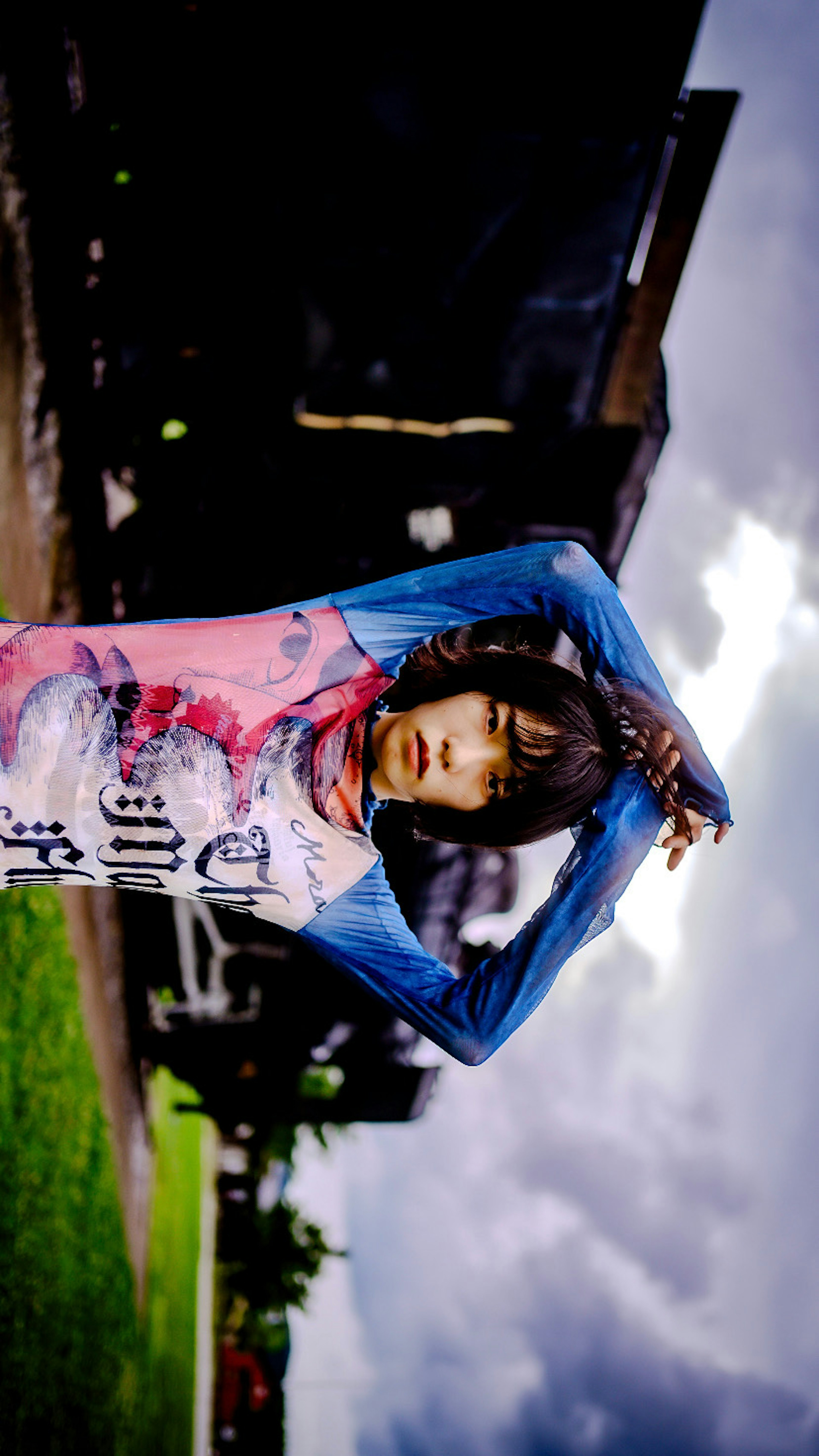 Woman in blue and pink tie-dye shirt raising her arms