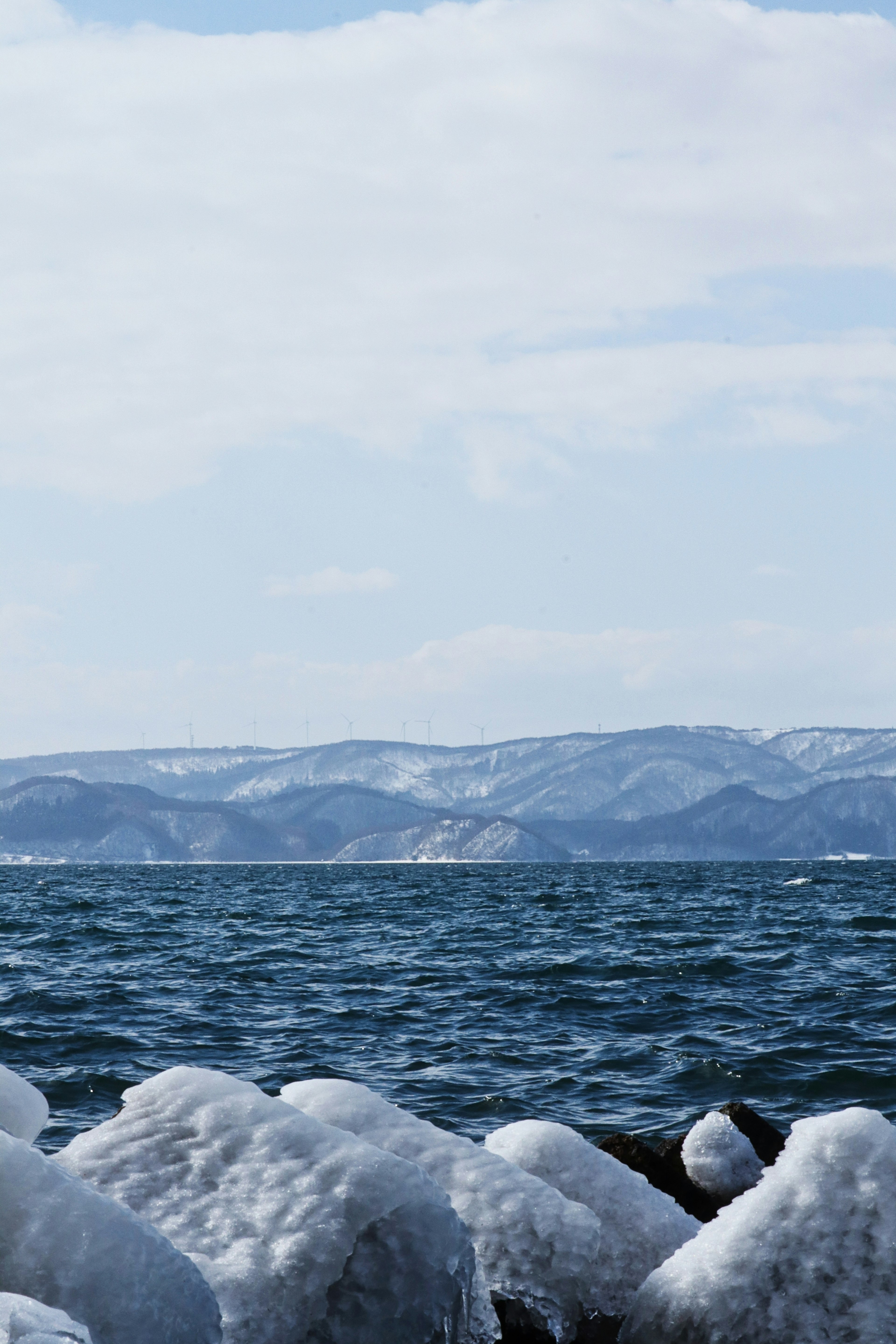 Coastline with icy rocks and snow-covered mountains in the background