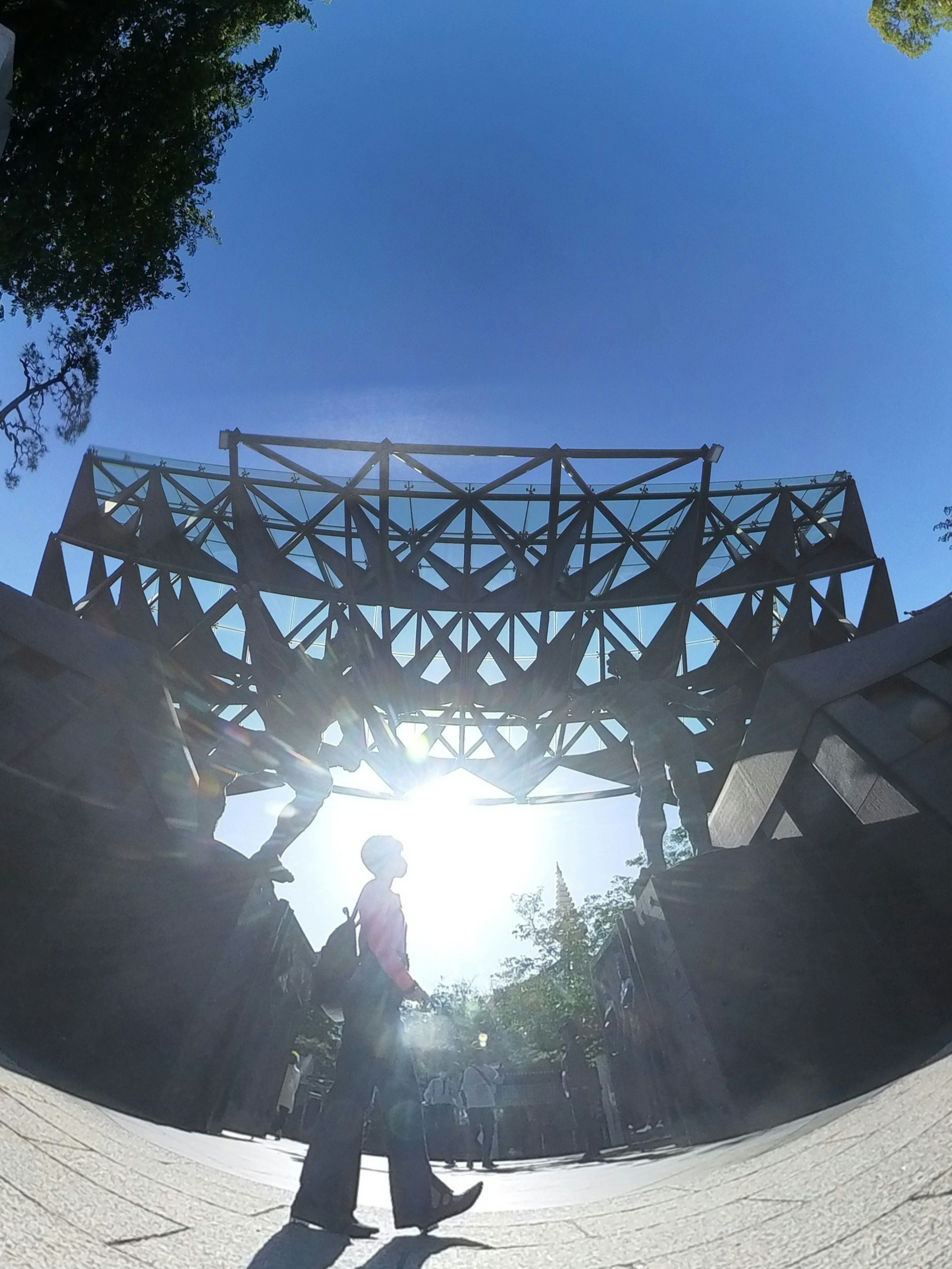 Silhouette d'une personne marchant sous une structure avec la lumière du soleil en arrière-plan