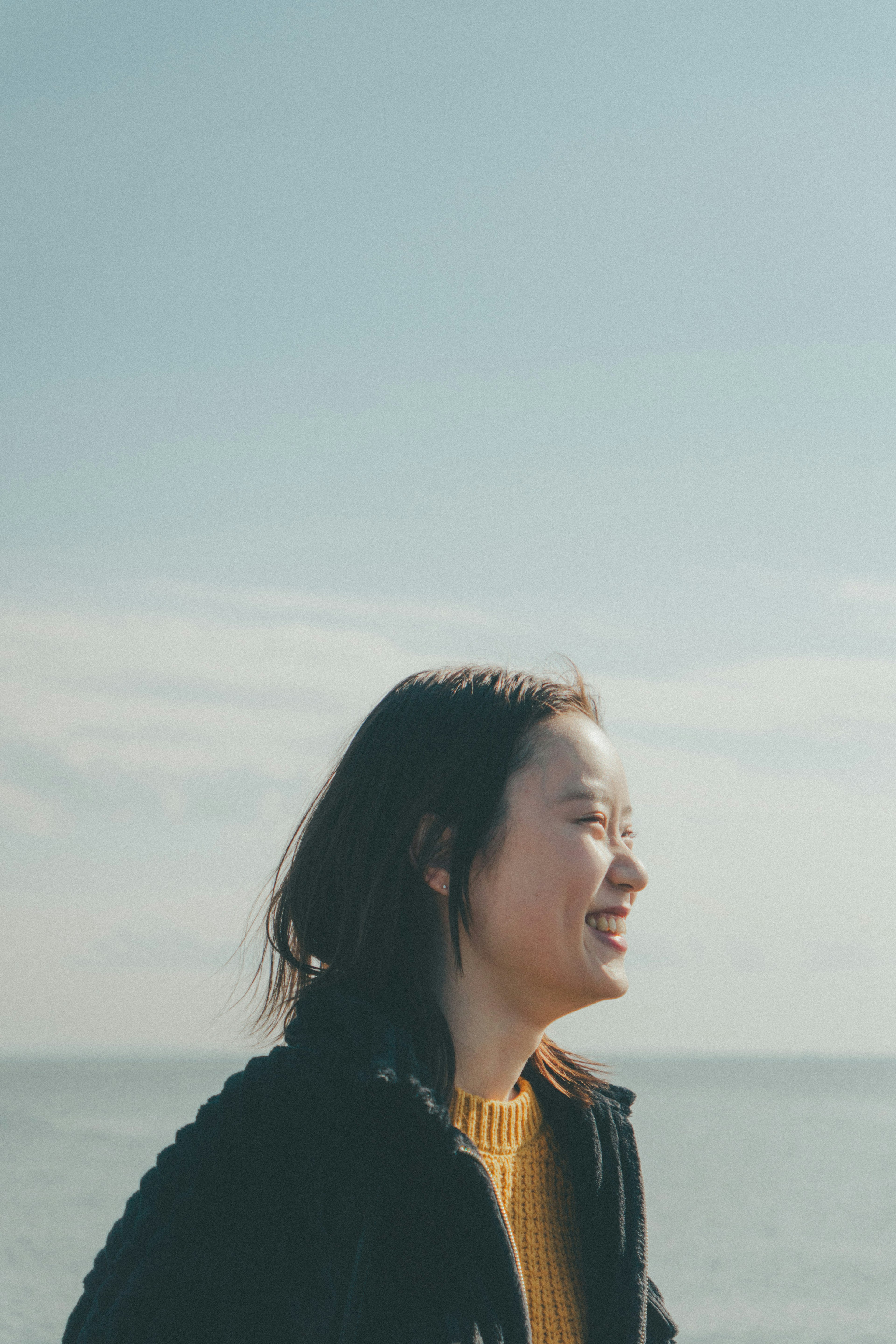 푸른 하늘 아래 미소 짓는 여성의 측면