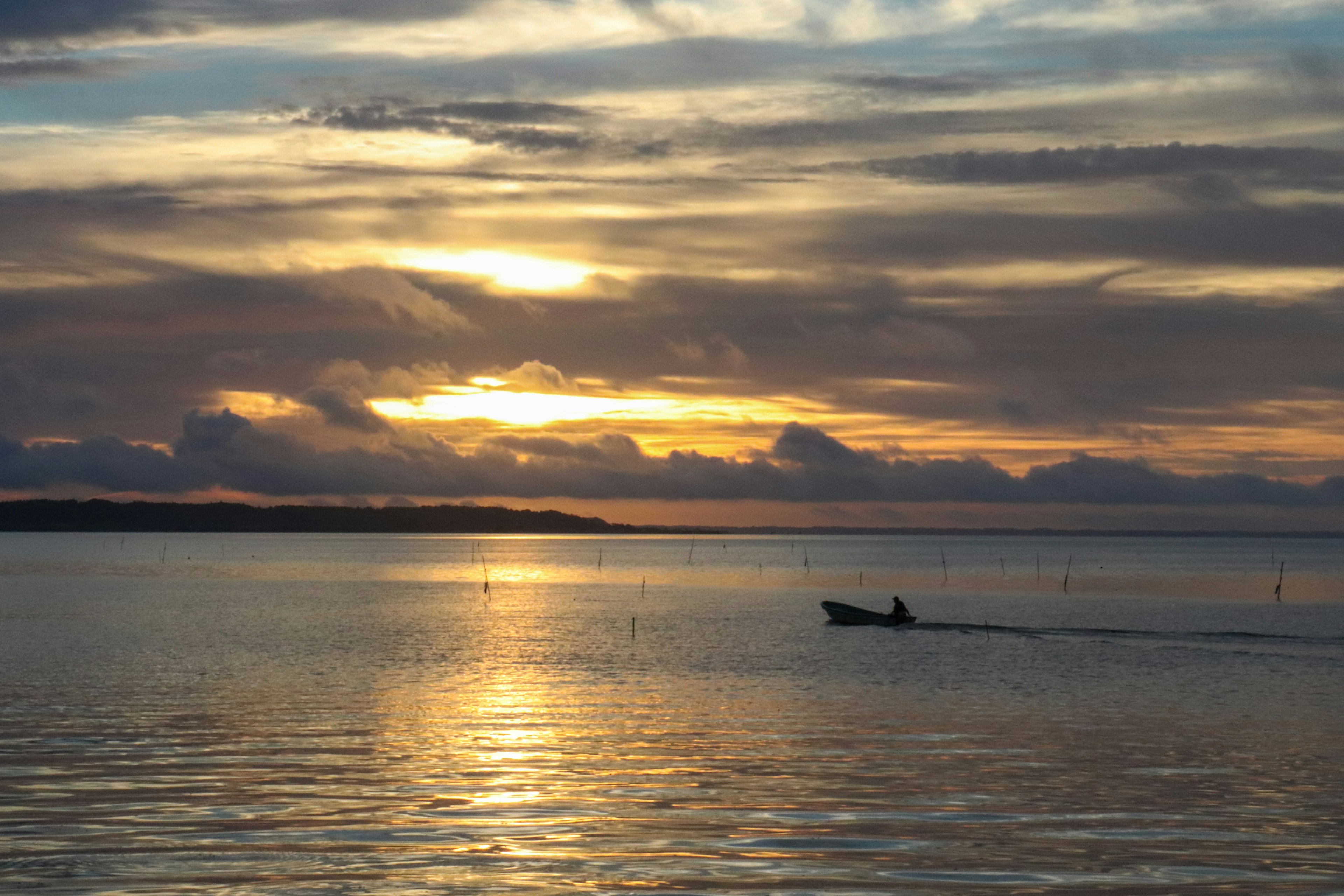 Un petit bateau glissant sur une mer calme reflétant le coucher de soleil